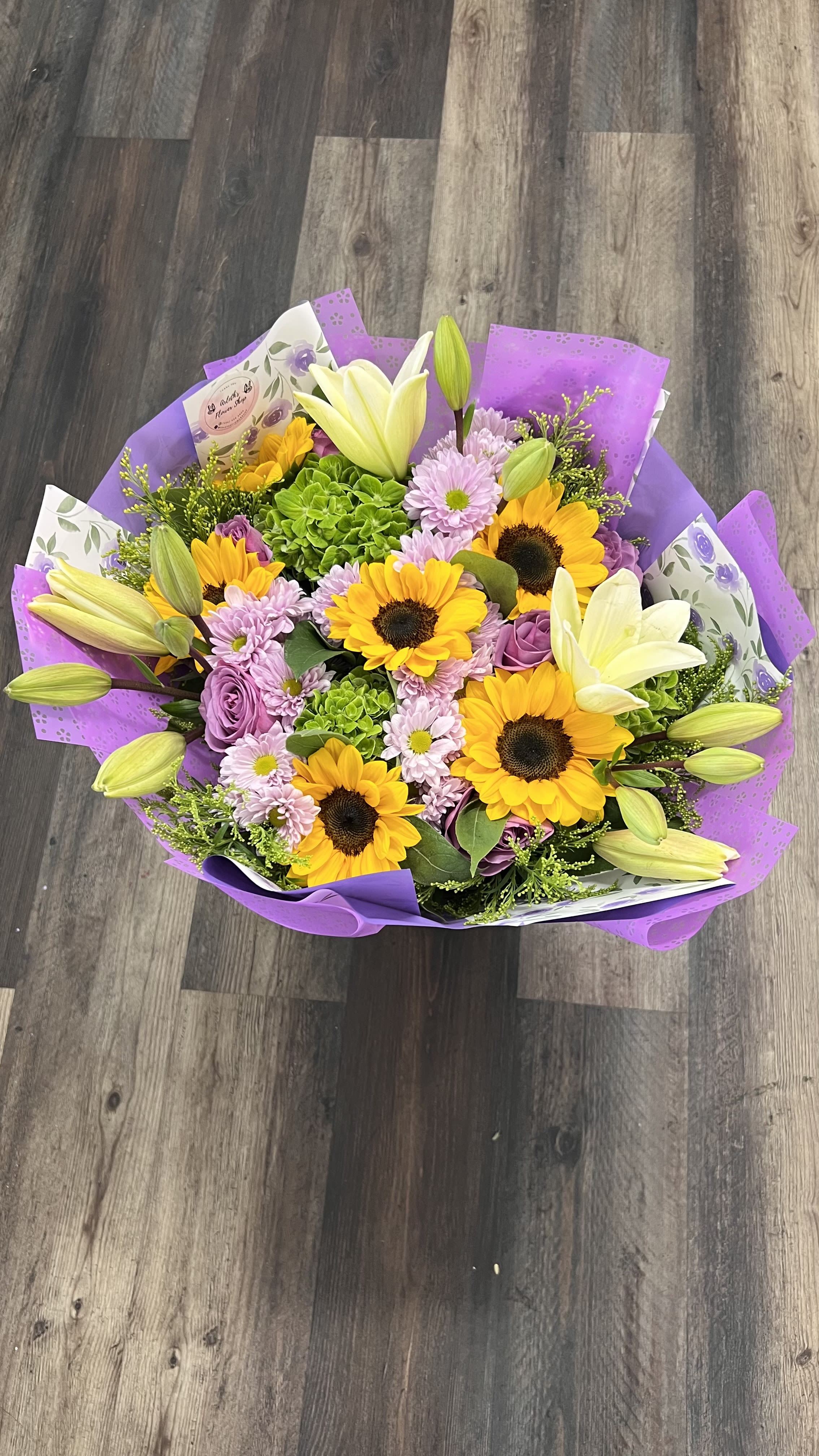  Spring Melody Bouquet  - A vibrant mixed bouquet featuring cheerful sunflowers, elegant white lilies, soft lavender daisies, roses, and lush green hydrangeas. A beautiful arrangement that brings warmth, joy, and elegance to any occasion.