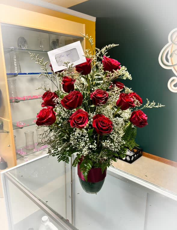 Red roses arranged in a vase with baby's breath and greenery