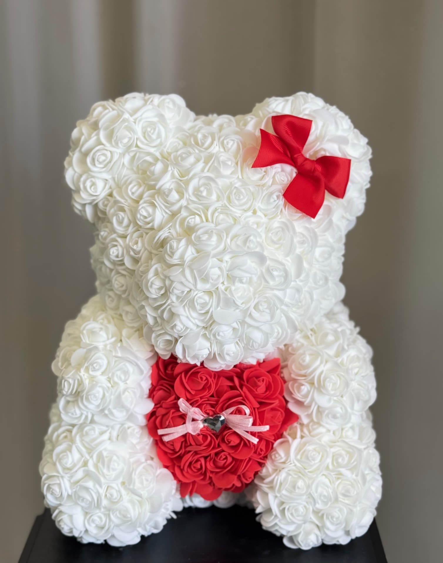 Faux White Rose Teddy Bear with Heart <3  - Each lovely, Styrofoam, Rose Teddy Bear is 100% handmade and covered with soft, faux, rose petals that are individually added. Each bear arrives in a window display box that is 15 in height and 11 in width, perfect for sitting on a shelf or table. They're designed to be durable and will last a lifetime if handled with care. They make a beautiful and eye-catching decoration in any room or even at the office. Every time she looks at it, she'll remember that special day. What a sweet memento!  Bear Dimension: 13" H x 10"W 