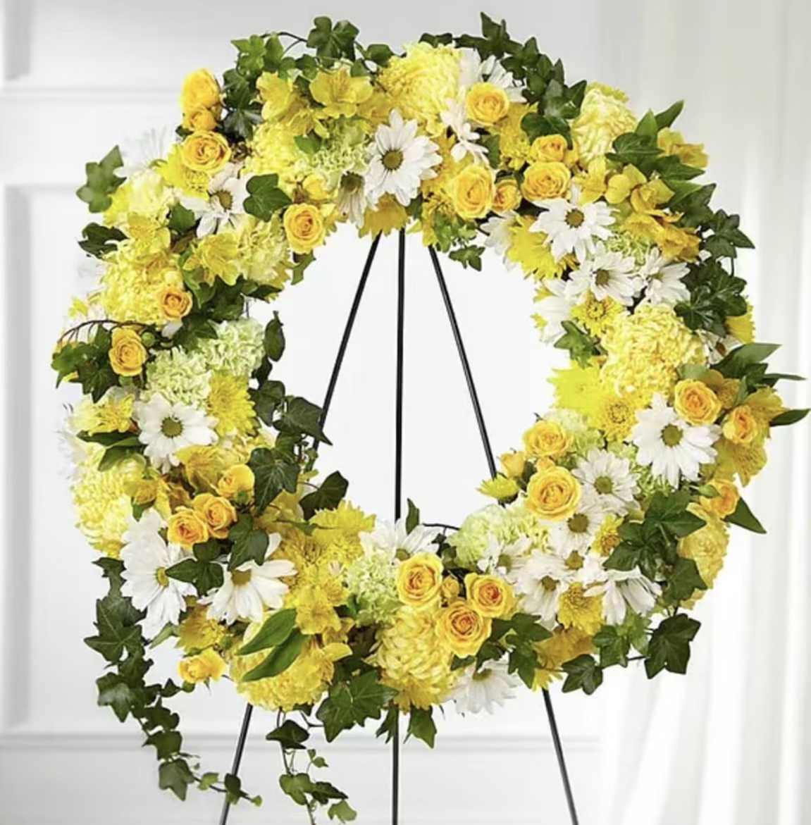 Yellow and white floral wreath on a black stand