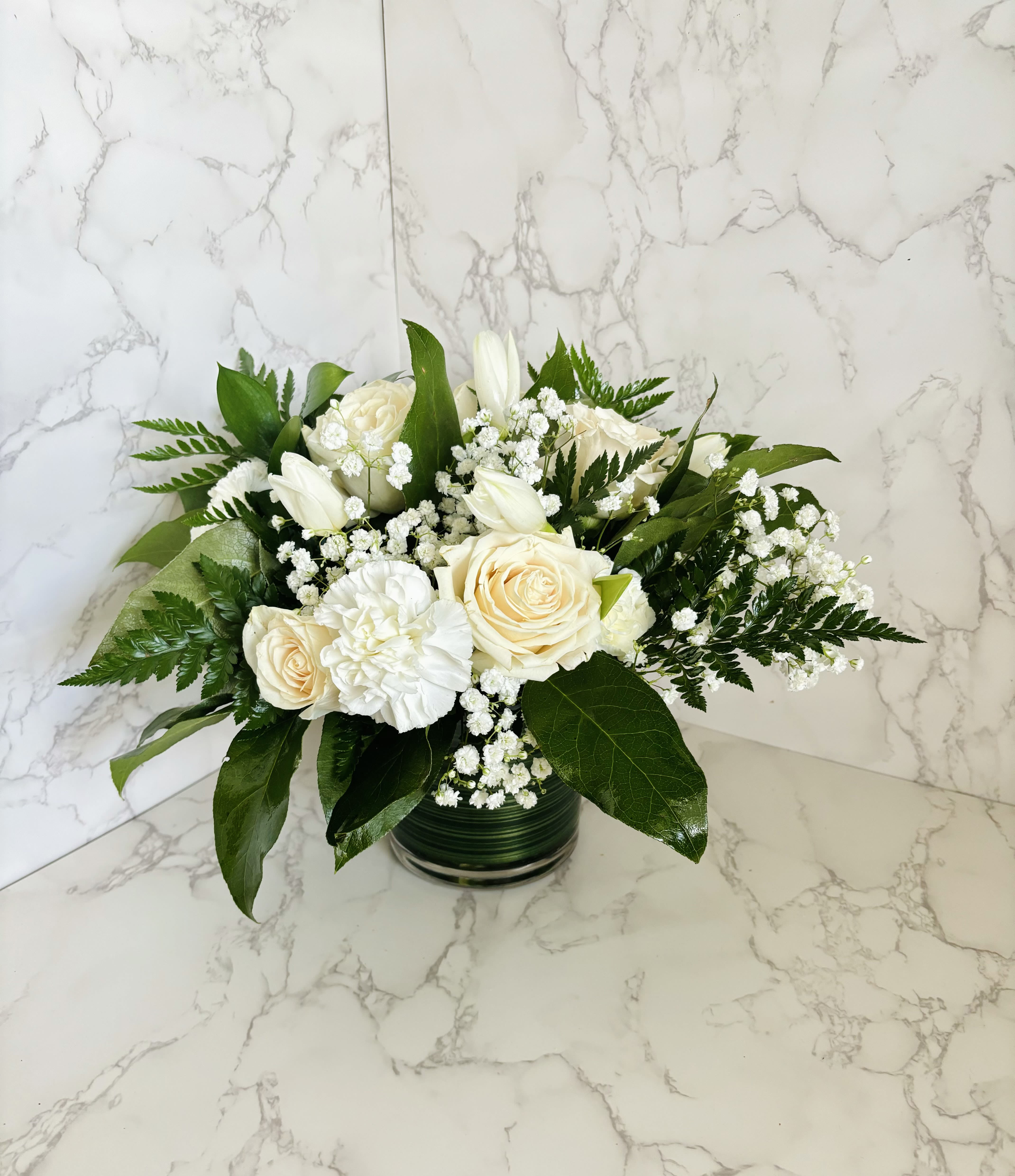 White roses and tulips arranged in a glass vase