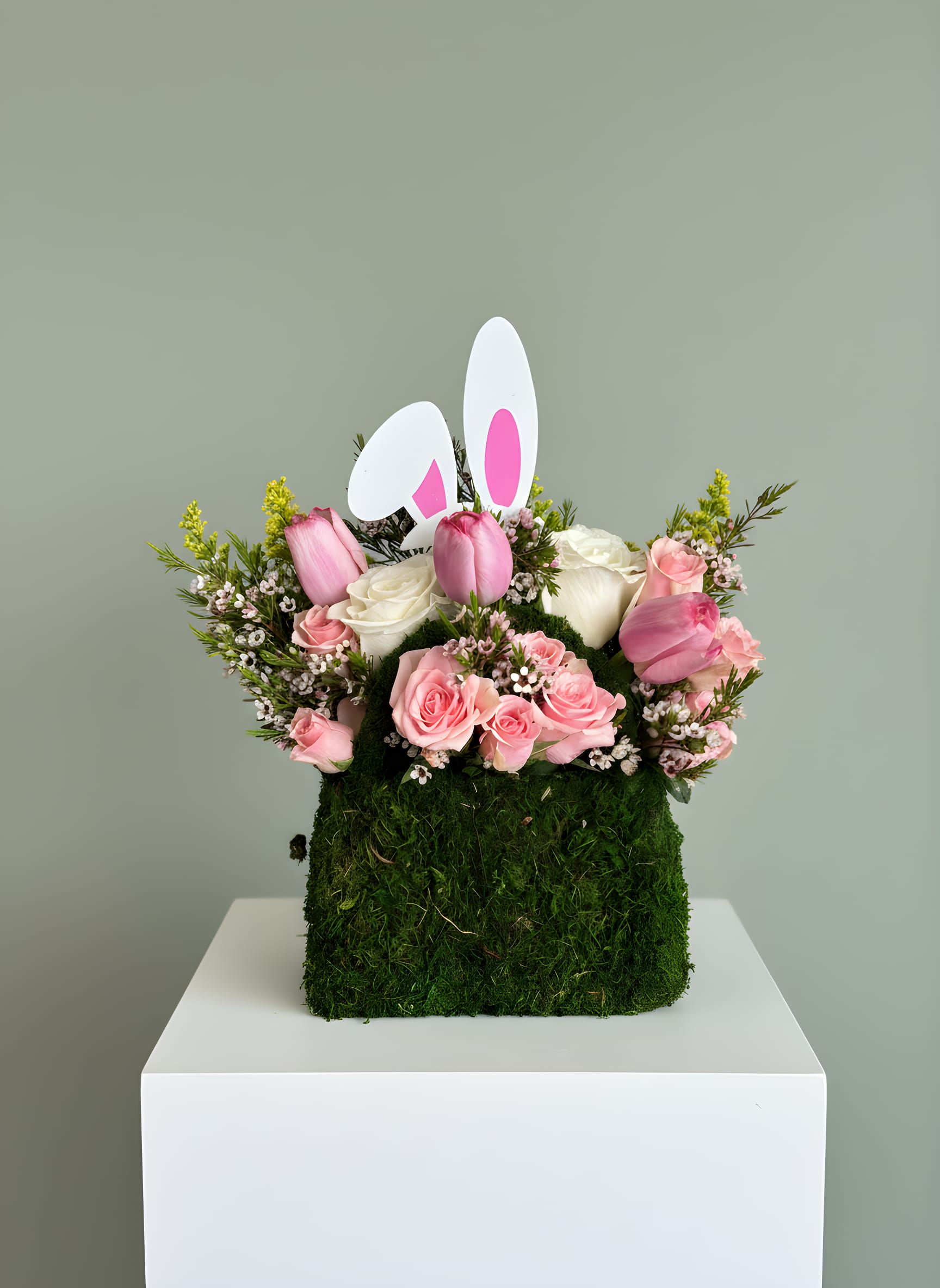 Blush Spring Bunny Arrangement - Celebrate the beauty of spring with this charming and elegant bunny-inspired floral design. Featuring a soft blend of blush pink roses, fresh tulips, and delicate seasonal blooms, this arrangement is designed in a unique moss-covered base and accented with a playful bunny detail for a whimsical yet refined touch.  Perfect for Easter gifting, spring celebrations, or simply brightening someone’s day, this piece combines softness, texture, and seasonal charm in one unforgettable design.   Ideal for: • Easter gifts • Spring décor • Birthdays &amp; special surprises • Children &amp; family celebrations  Please note: Flower varieties may vary based on availability, while maintaining the same color palette, style, and overall fullness of the design.