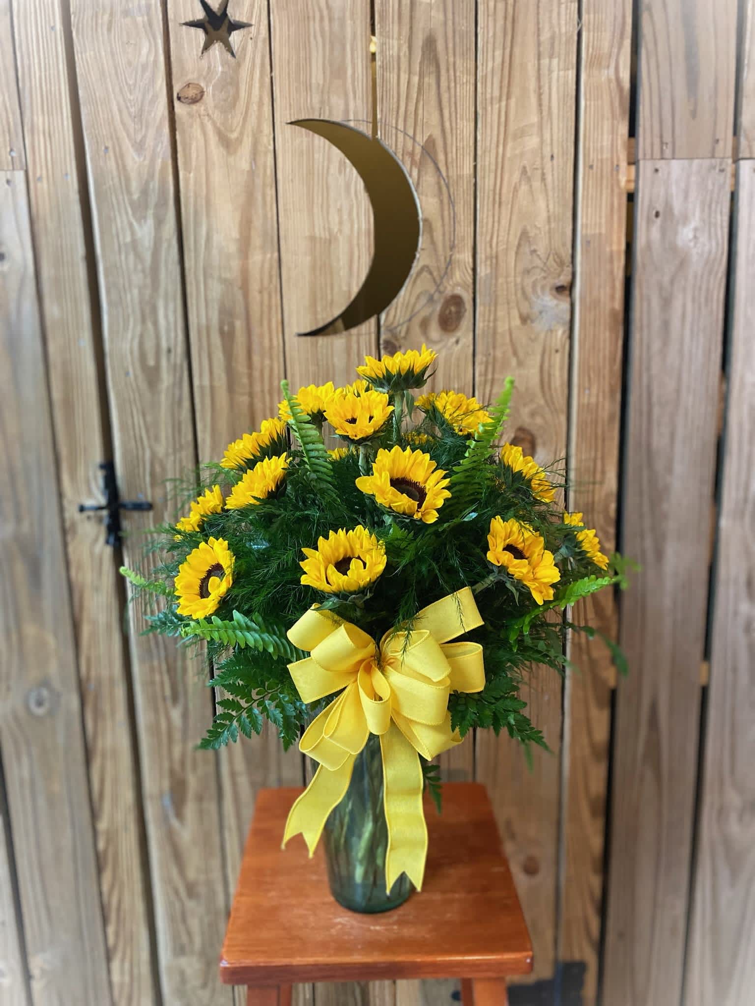 Yellow sunflower arrangement in a glass vase with a ribbon bow