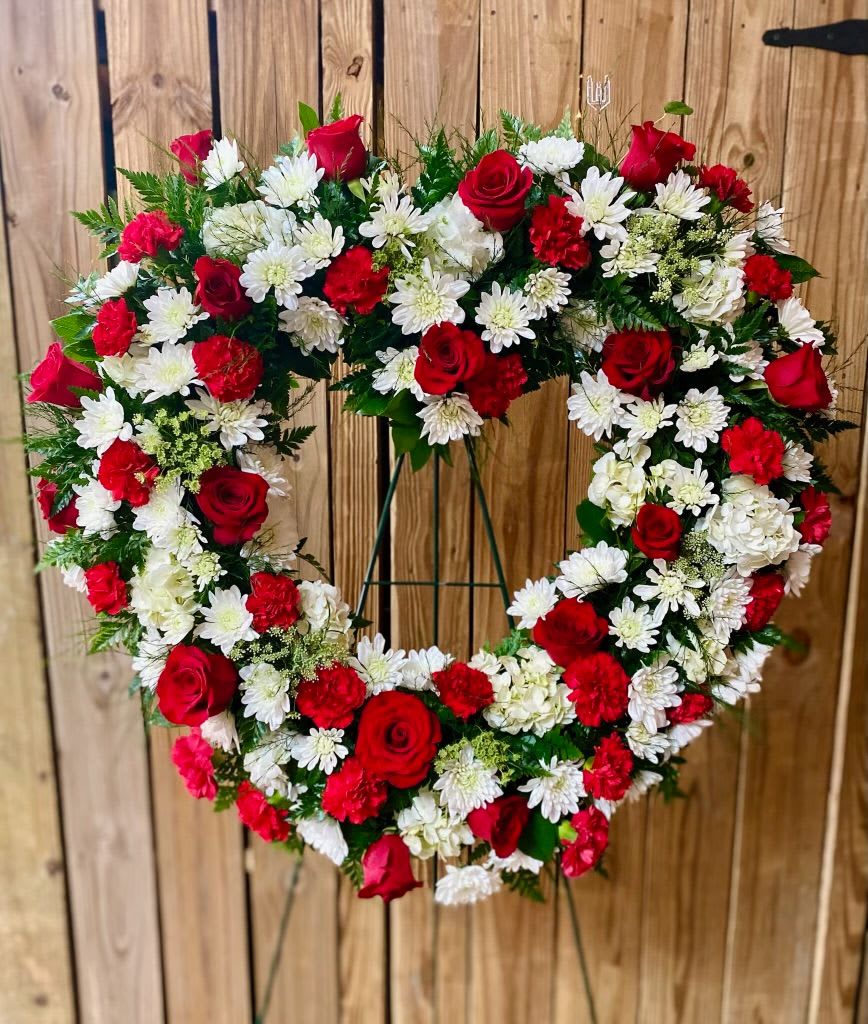 Heart-shaped wreath of red roses and white daisies on a stand