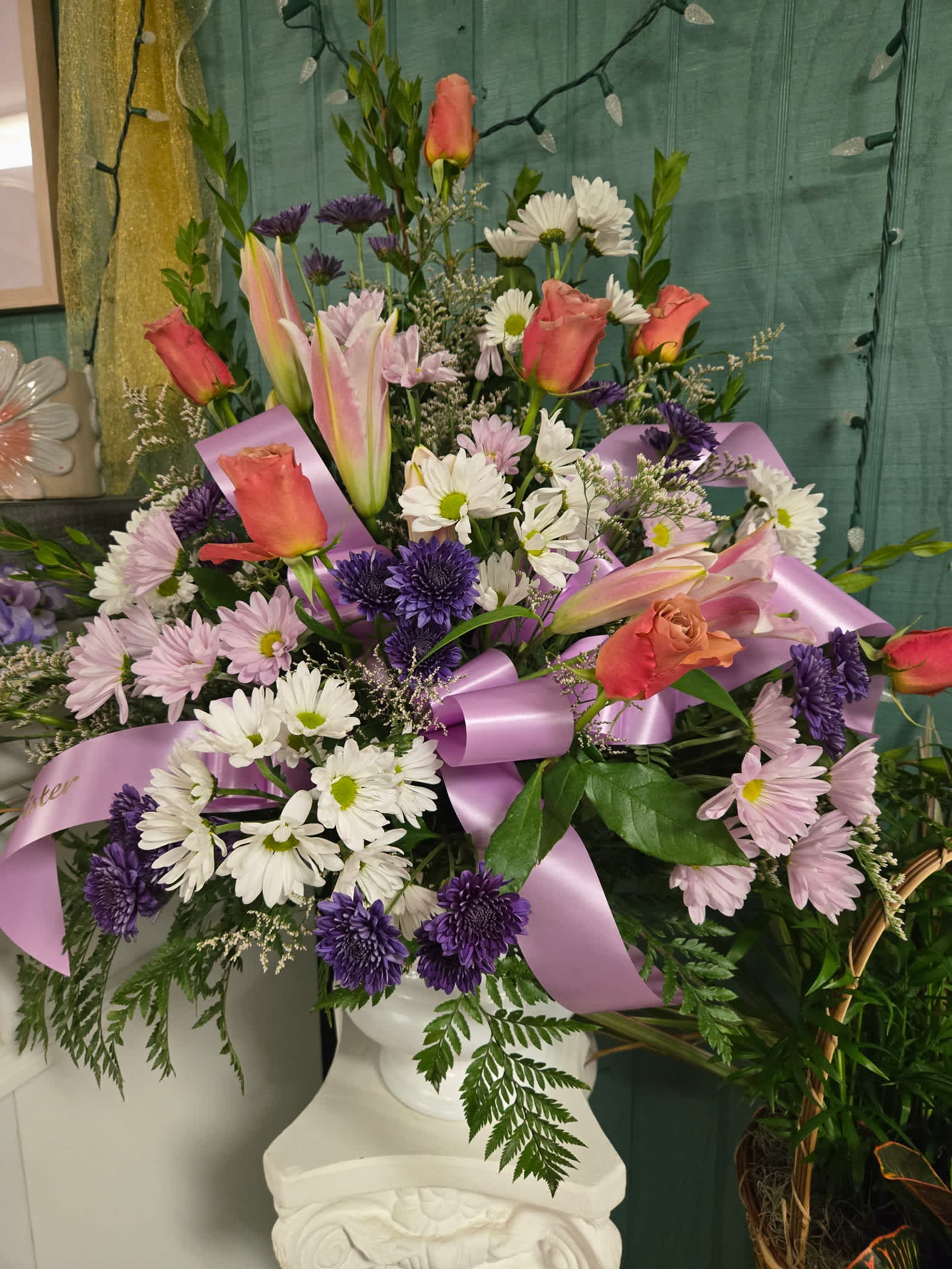 Mixed bouquet with pink roses, lilies, and purple daisies tied with lavender ribbon