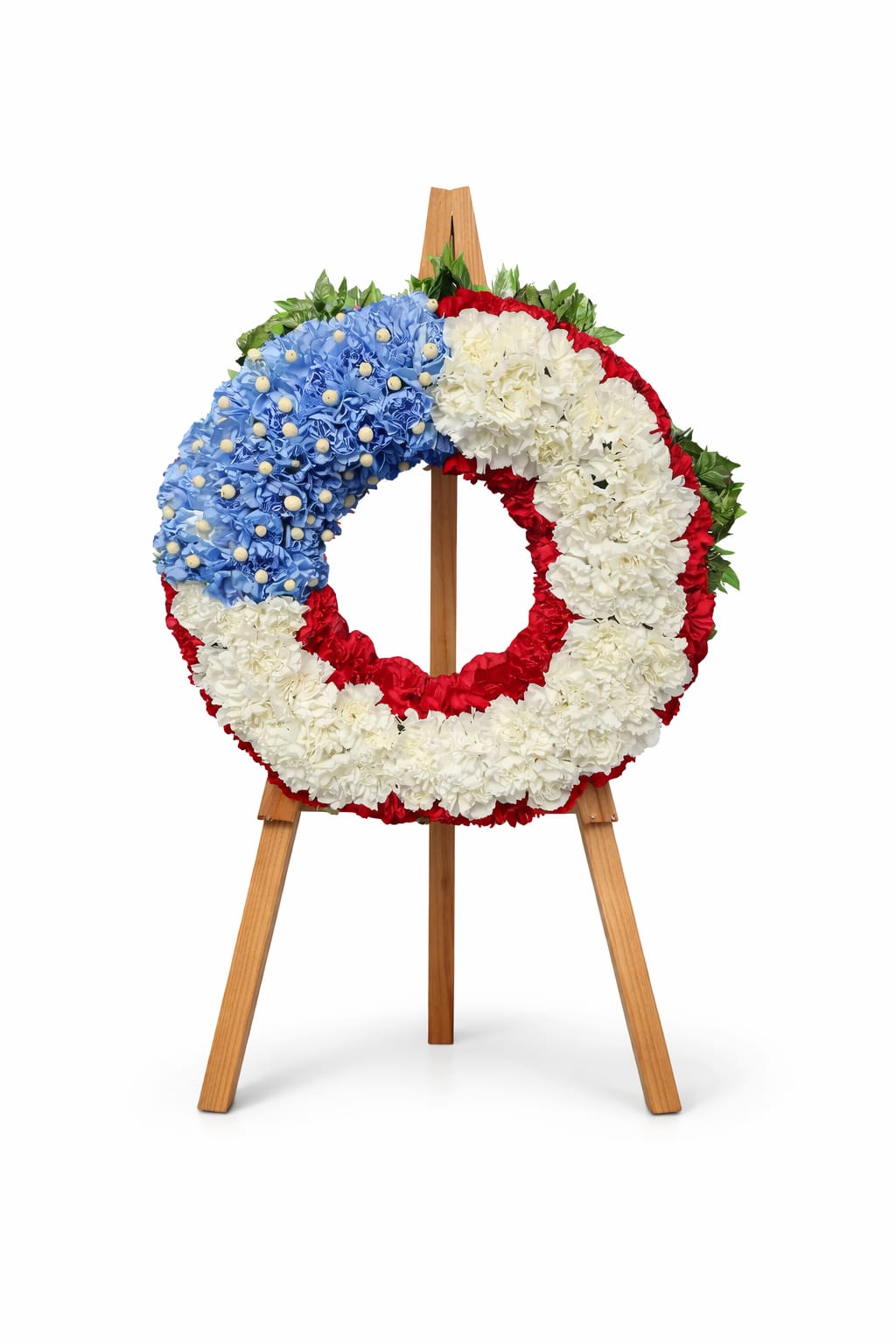  Stars &amp; Stripes Memorial Wreath - Honor the brave souls who served our country with our Stars and Stripes Memorial wreath. This exquisite floral arrangement, adorned in vibrant red, white, and blue, serves as a heartfelt tribute to their sacrifice. Perfect for memorial services, anniversaries, or simply to show your respect, this wreath captures the spirit of patriotism and remembrance. Make a lasting impression and celebrate their legacy with this stunning piece that speaks volumes of gratitude and honor.  Our designers work carefully to capture the essence of your selected arrangement. Because flowers vary by season and nature, substitutions in color or type may be needed. Please note that seasonal changes can also influence pricing and availability. Don't forget to include your desired script in the notes section for a personal touch!