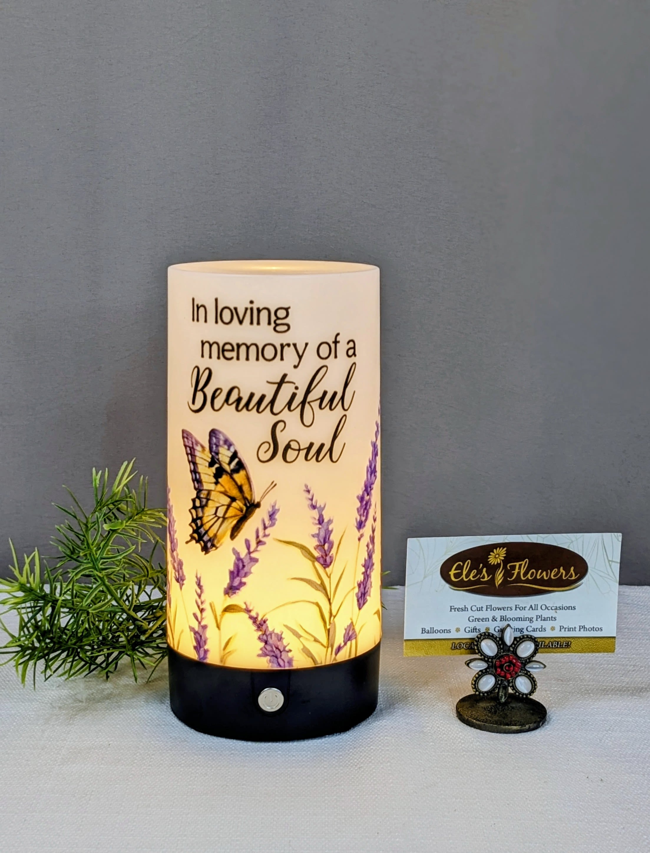 Memorial candle with butterfly and lavender design beside a small card holder