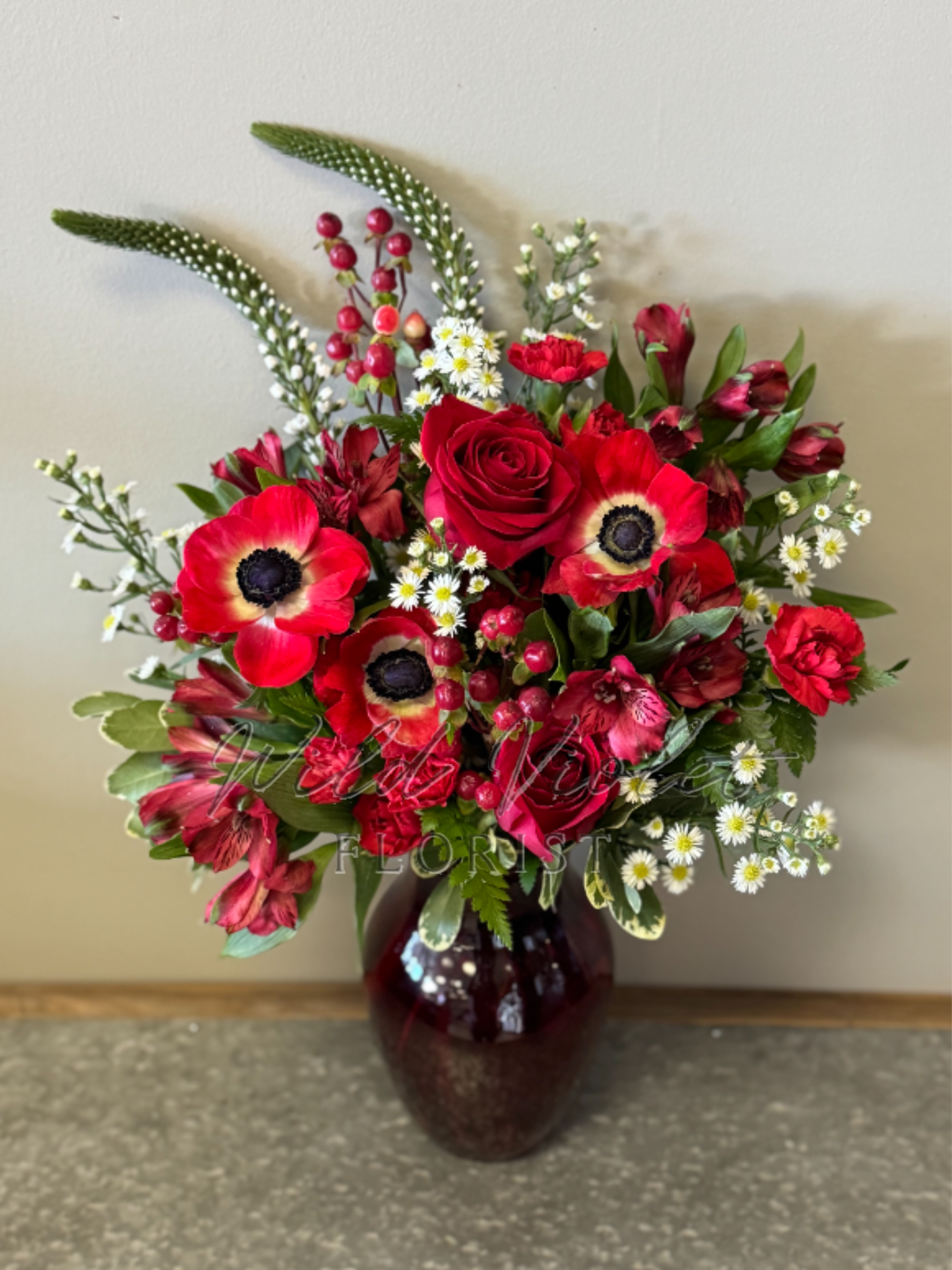 July Ruby Bouquet - Birthstone Collection What better way to celebrate your loved one's birthday than with our July Ruby Bouquet! Hand-designed with a stunning gathering of vibrant reds and white blooms, lush greenery and in a ruby vase, it’s a thoughtful sentiment filled with the passion and power of a ruby stone.  ATTENTION! If you are ordering this arrangement on a different month other than what it's respected month is, there will be substitutions for certain flowers depending on seasonal availability. We will stay within the same color scheme and design style!  PLEASE NOTE: Florist reserves the right to make modifications to the design based on seasonality and accessibility of blooms and vases. Any modifications made will honor the palette, intent, and feeling of the pictured design. Contact floral designer directly with any specifications or concerns.