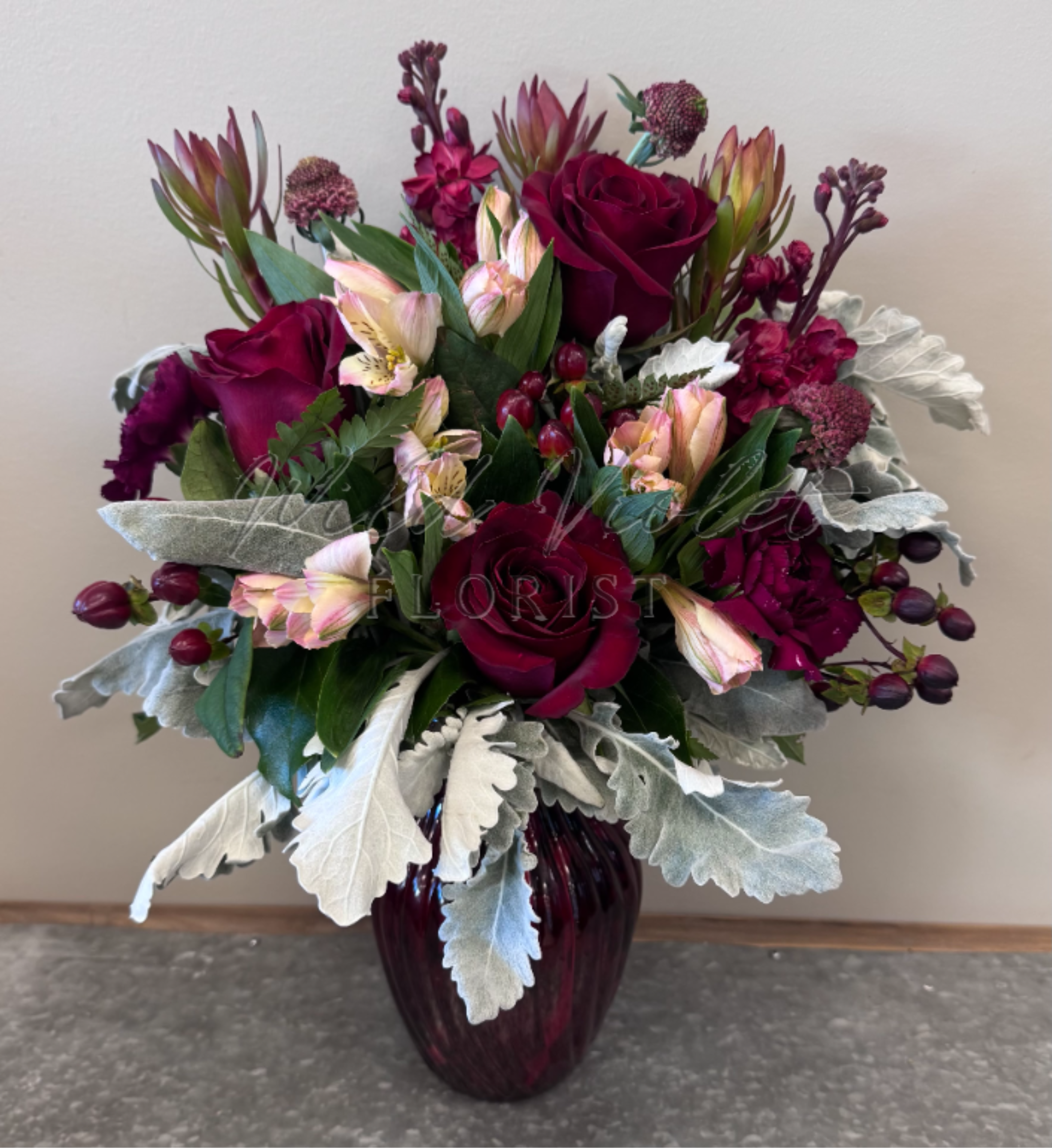 January Garnet Bouquet - Birthstone Collection What better way to celebrate your loved one's birthday than with our January Garnet Bouquet!  Hand-designed with a lush gathering of burgundy blooms, evergreens and silver touches, it’s a thoughtful sentiment filled with the deep, rich beauty of a garnet stone.  ATTENTION! If you are ordering this arrangement on a different month other than what it's respected month is, there will be substitutions for certain flowers depending on seasonal availability. We will stay within the same color scheme and design style!  PLEASE NOTE: Florist reserves the right to make modifications to the design based on seasonality and accessibility of blooms and vases. Any modifications made will honor the palette, intent, and feeling of the pictured design. Contact floral designer directly with any specifications or concerns.
