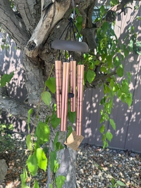 Rose-gold wind chime hanging from a tree branch