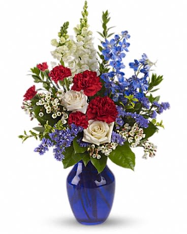 Mixed bouquet of red, white, and blue flowers in a cobalt vase