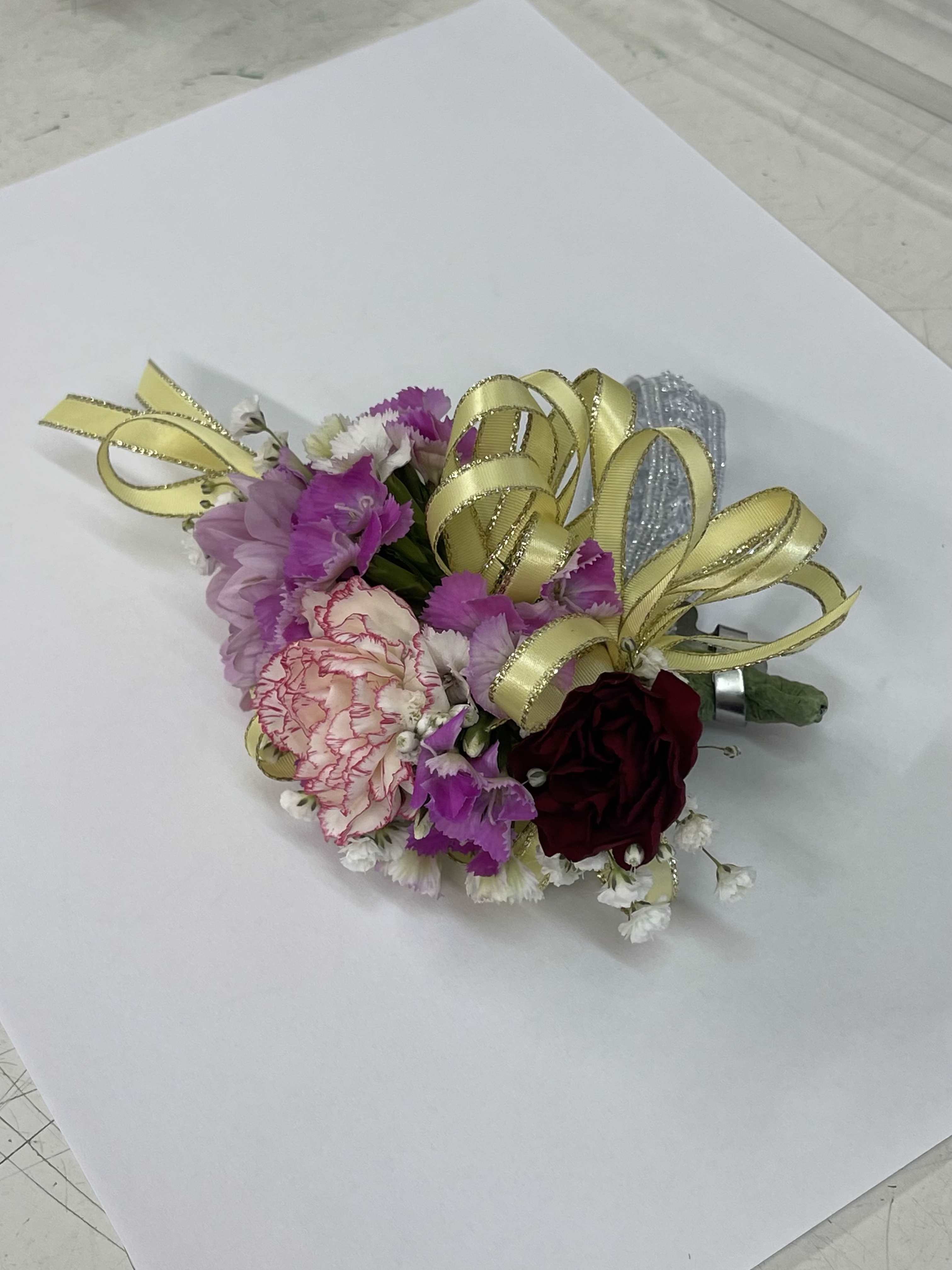 Small corsage with pink and burgundy flowers and gold ribbon loops