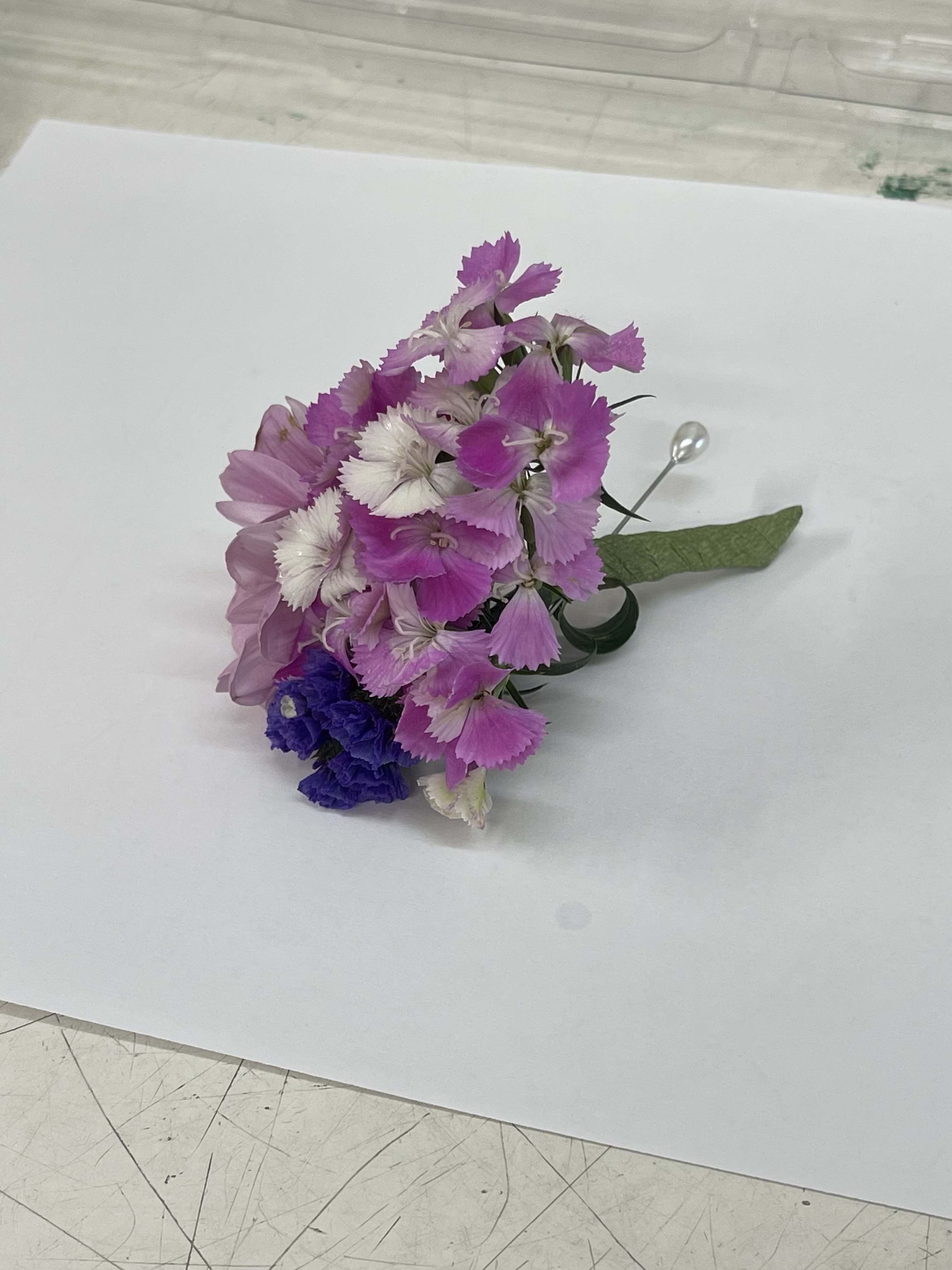 Small corsage with pink and white flowers and a green ribbon
