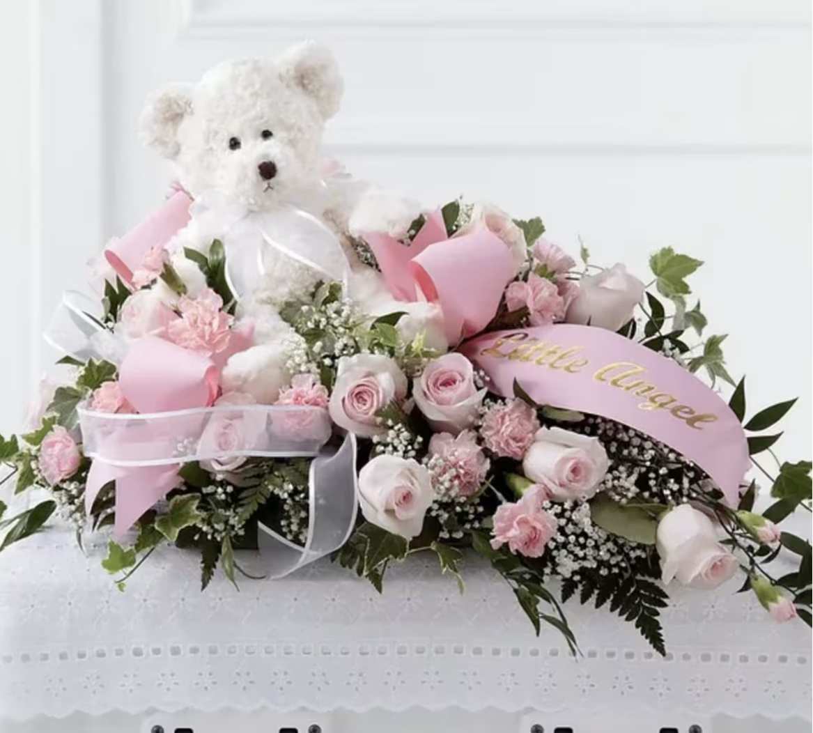 Pink rose arrangement with a white teddy bear and ribbon accents