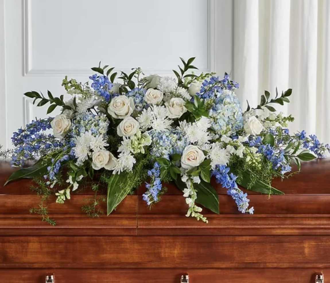 White and blue floral arrangement on a casket