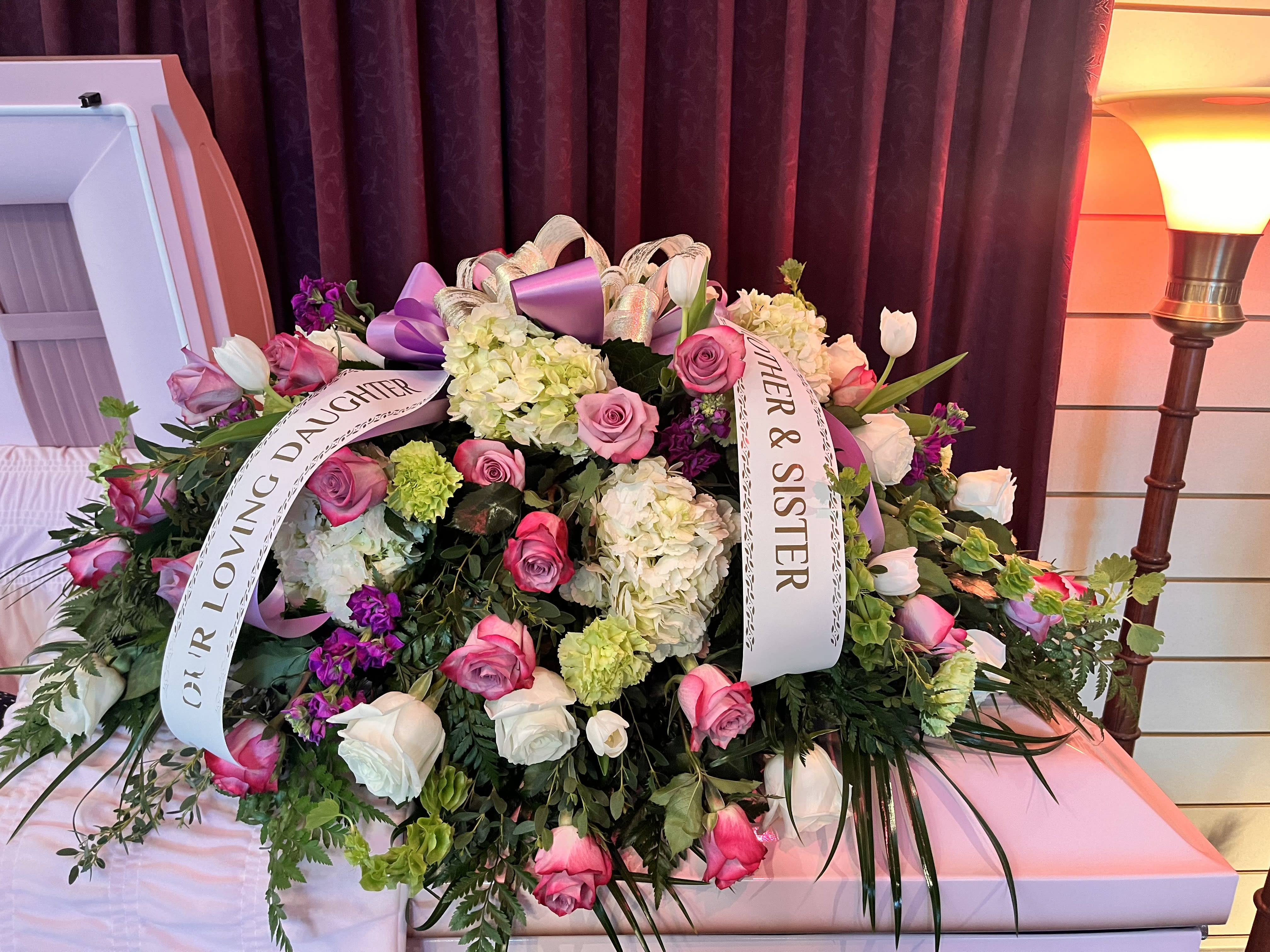 Lavender tribute casket  - A collection of lavender roses, hydrangeas, tulips, stock, and various greens. 