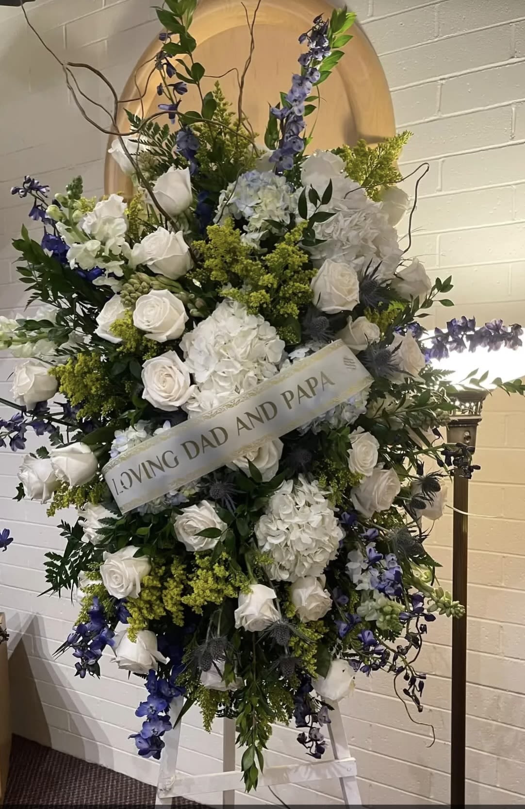 Large white and blue funeral spray with roses and hydrangeas