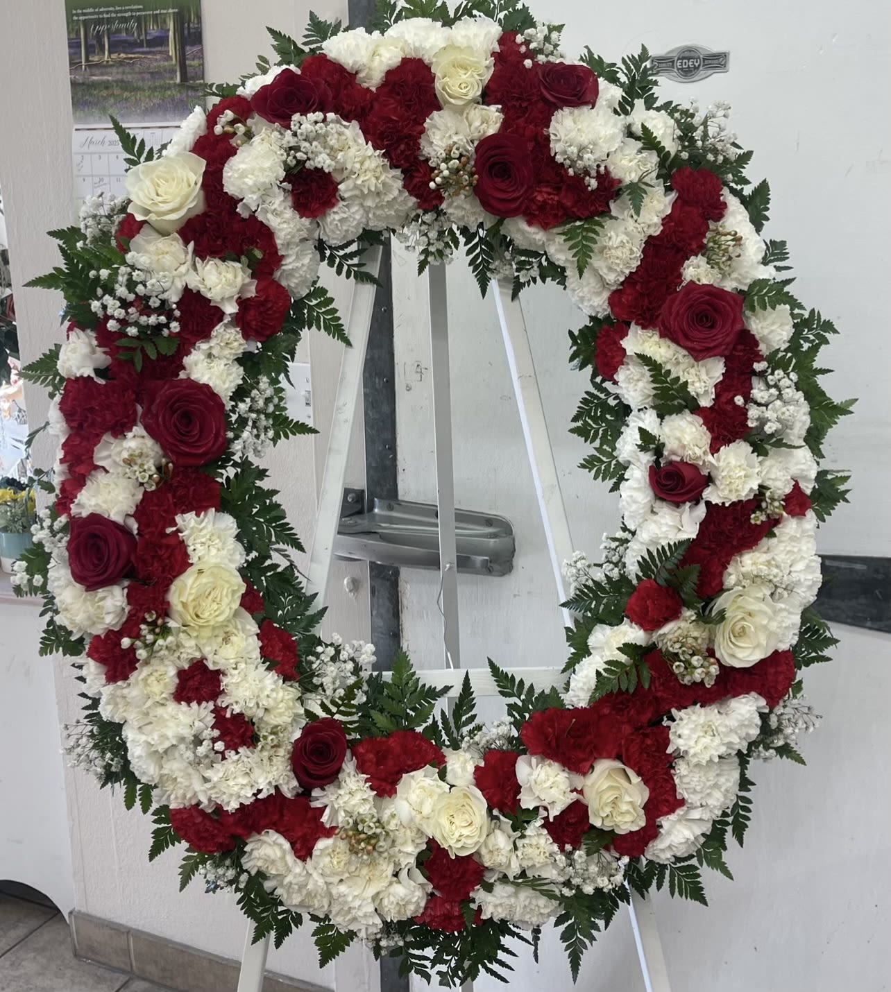 Large red and white floral wreath on a stand