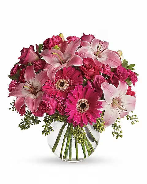 Pink lilies, roses, and gerbera daisies in a clear glass vase