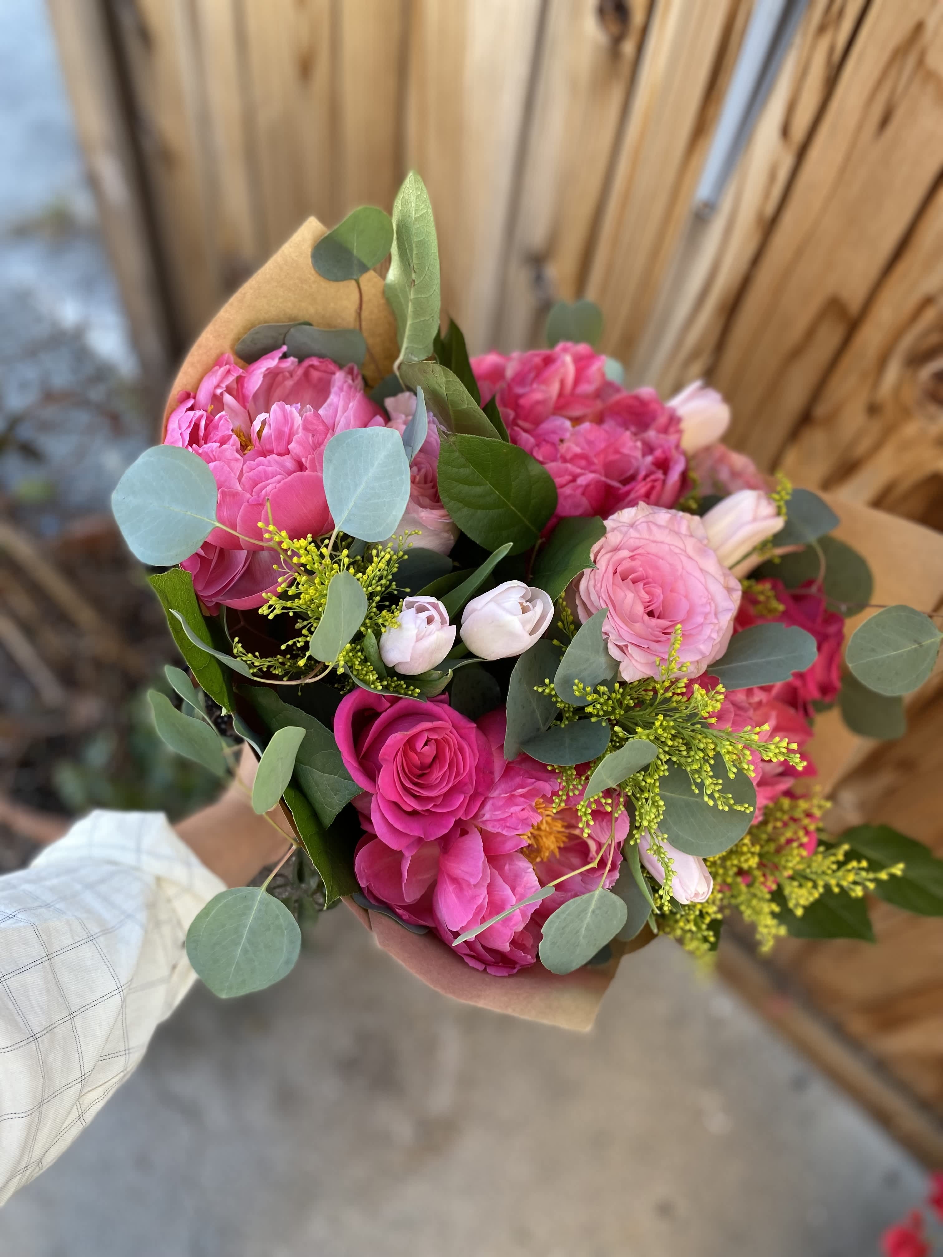 Pink mixed bouquet wrapped in brown paper with eucalyptus