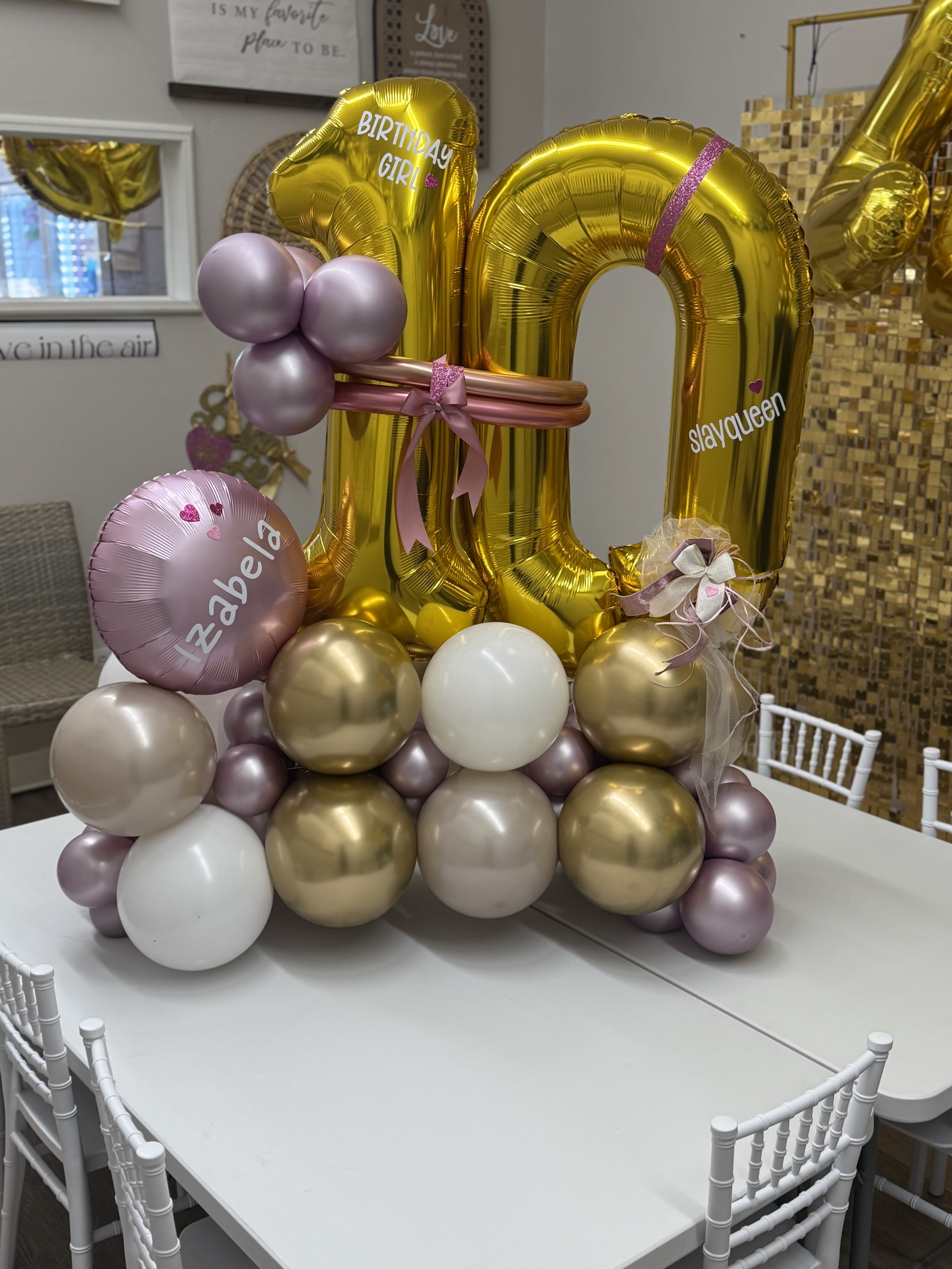 Gold birthday balloon display with pink and lavender accents on a table