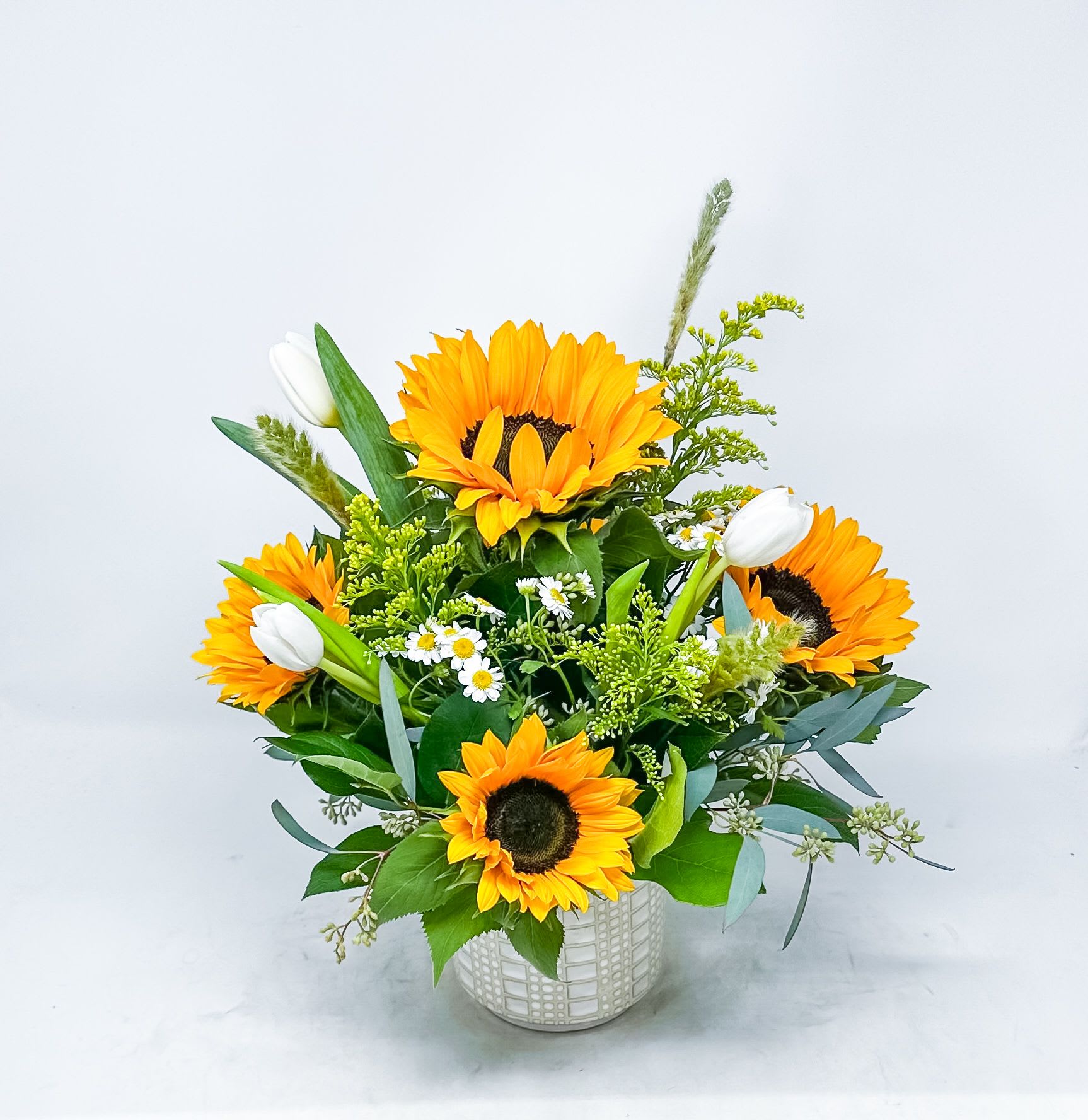 Sunflower bouquet in a white patterned vase with white tulips