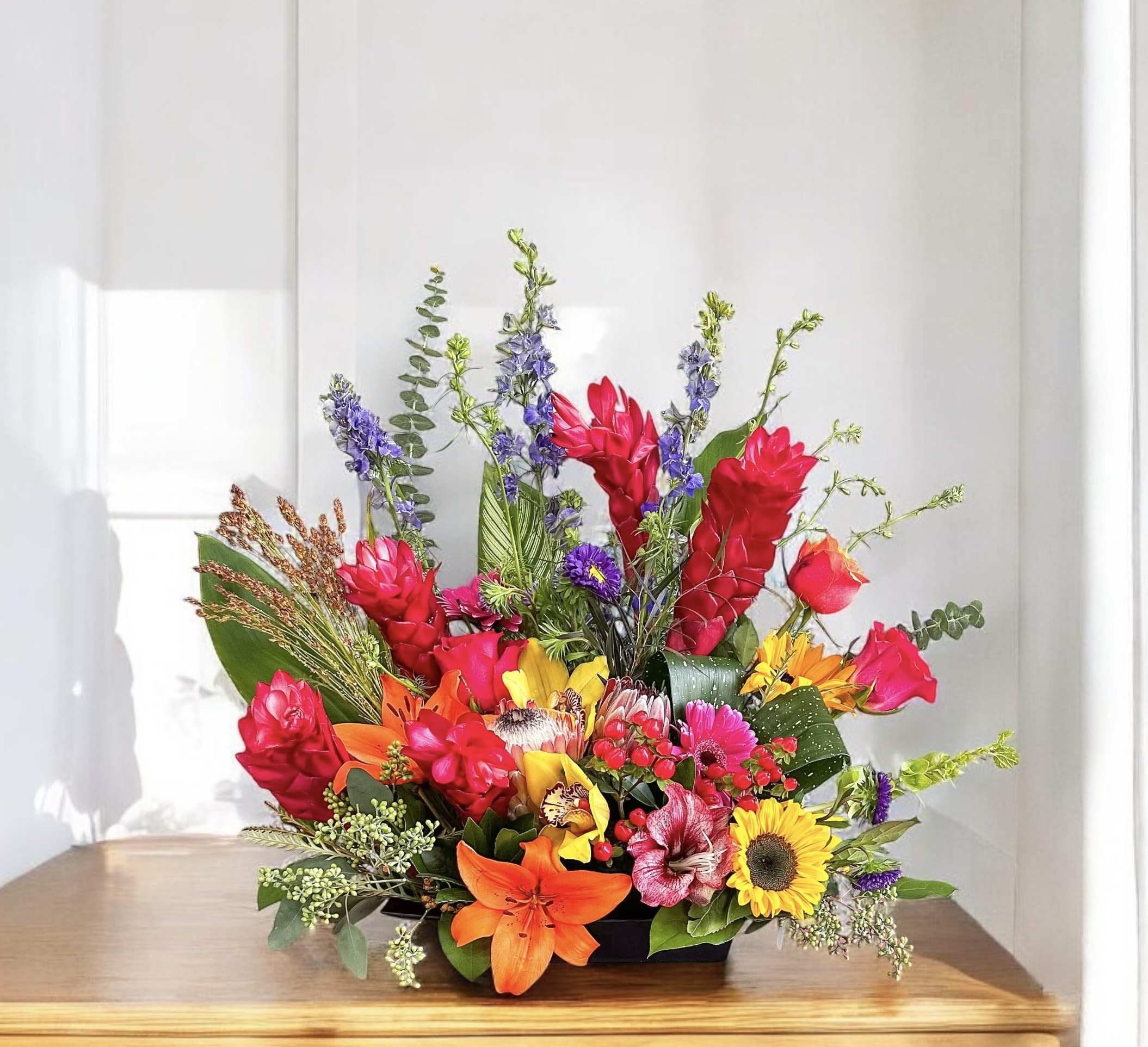 Bright mixed flower arrangement in a low black container