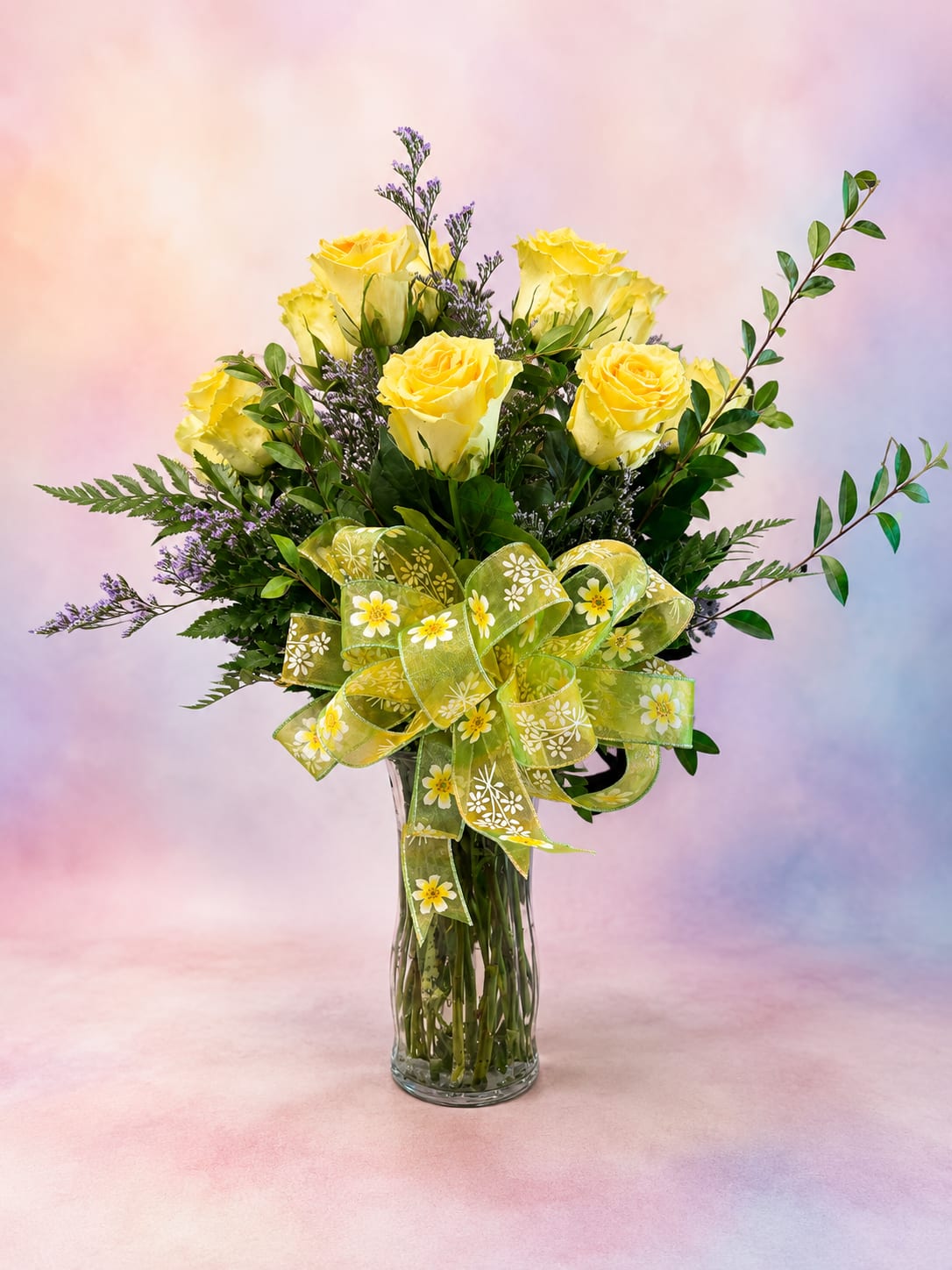 Sweet Lemonade Dreams - Bright, cheerful, and full of sunshine, Sweet Lemonade Dreams features a classic dozen buttery yellow roses accented with airy purple statice and lush premium greenery. Finished with a whimsical lemon-and-daisy ribbon, this joyful arrangement brings the fresh, uplifting feeling of a glass of homemade lemonade on a warm summer afternoon. Whether you're celebrating a birthday, sending encouragement, or simply brightening someone's day, this bouquet delivers a refreshing splash of happiness and heartfelt smiles.