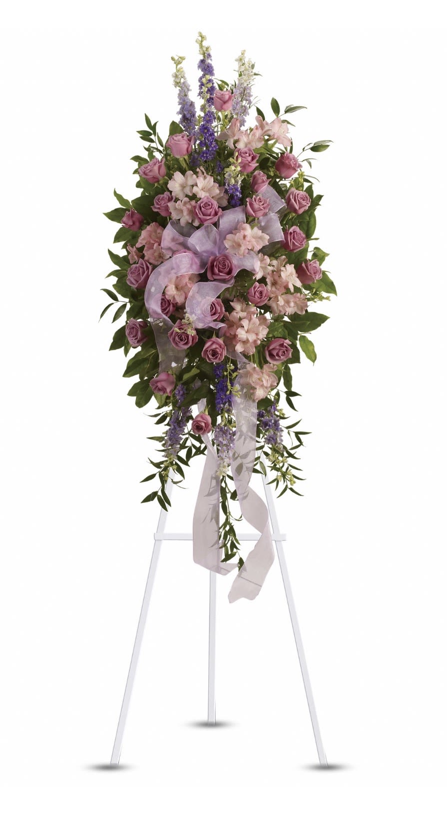 Finest Farewell Spray - A tall standing sympathy spray that reads with quiet elegance - the Finest Farewell Spray is crafted for memorial and funeral services when you want the person you're thinking of to feel honored and remembered. The arrangement centers on a dense cluster of pink roses and pale pink blooms that convey tenderness, while vertical spikes of purple and white delphinium and alstroemeria lift the composition, giving it a graceful, upward focus appropriate for a solemn service.  Layered greenery cascades outward and downward to soften the silhouette, creating a formal yet gentle shape that reads well from a distance on a white easel. A sheer lavender ribbon is woven through the center and trails below, adding a ceremonial touch and a hint of color contrast against the soft pinks and greens. Colors include pink, purple, white, green, and lavender; flowers used are roses, alstroemeria, and delphinium.  Designed to be placed on a white easel for viewings and services, this spray is the kind of tribute that helps loved ones feel seen and supported during a difficult moment. No special care is required from the recipient once arranged; if ordering, please confirm delivery details and service time so the piece arrives appropriately for the memorial.