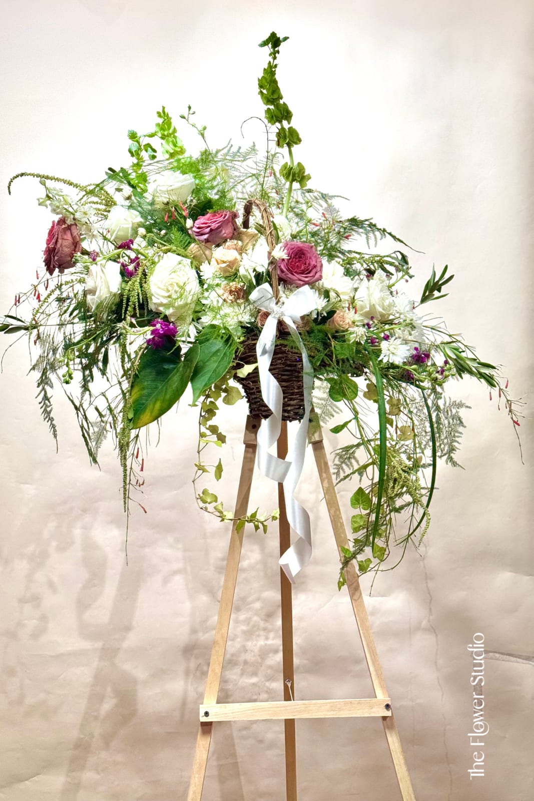 Whispering Meadow - An airy, garden-inspired arrangement with cascading lines and delicate textures, creating a soft and peaceful expression of beauty, arranged in a beautiful basket. Approx: W 30x H 32 (not includig easel height)