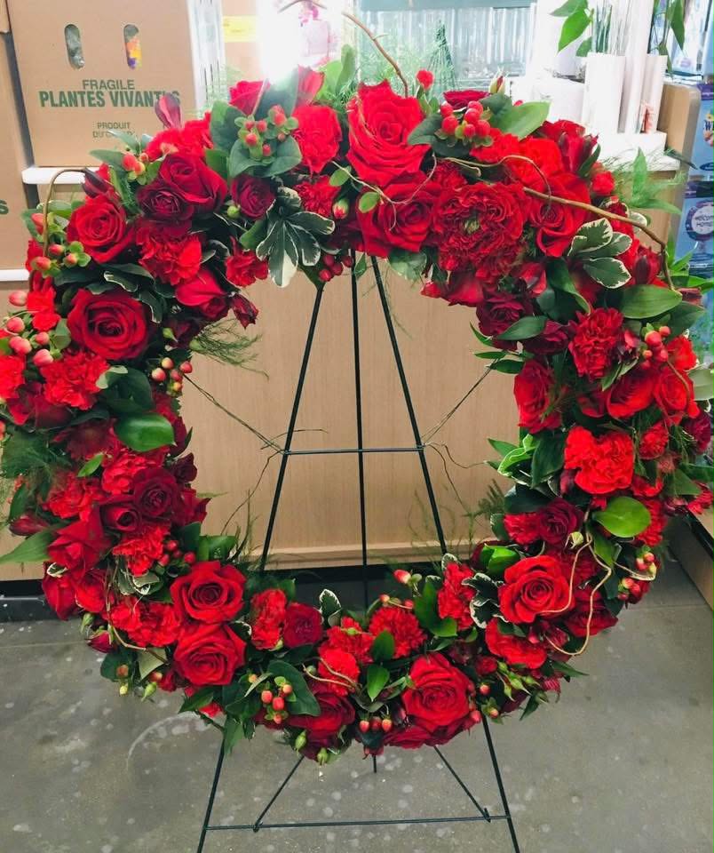 Sympathy Wreath – Red Rose Funeral Wreath - Honor the memory of a loved one with this elegant Red Rose Funeral Wreath, handcrafted with premium fresh flowers. Designed with luxurious red roses, red carnations, hypericum berries, and lush greenery, this standing wreath symbolizes love, respect, strength, and everlasting remembrance. Its timeless circular design represents eternal life and offers a heartfelt tribute for funeral services, memorials, and celebrations of life.  Each wreath is carefully arranged by our expert florists using the freshest seasonal blooms. Flower varieties may vary slightly to ensure the highest quality while maintaining the overall style and color palette. Perfect for:  * Funeral Services * Memorial Services * Celebration of Life * Sympathy Tributes * Cemetery Ceremonies  Features:  * Premium fresh red roses and carnations * Elegant standing wreath design * Handcrafted by professional florists * Includes easel stand * Same-day funeral flower delivery available in Miam