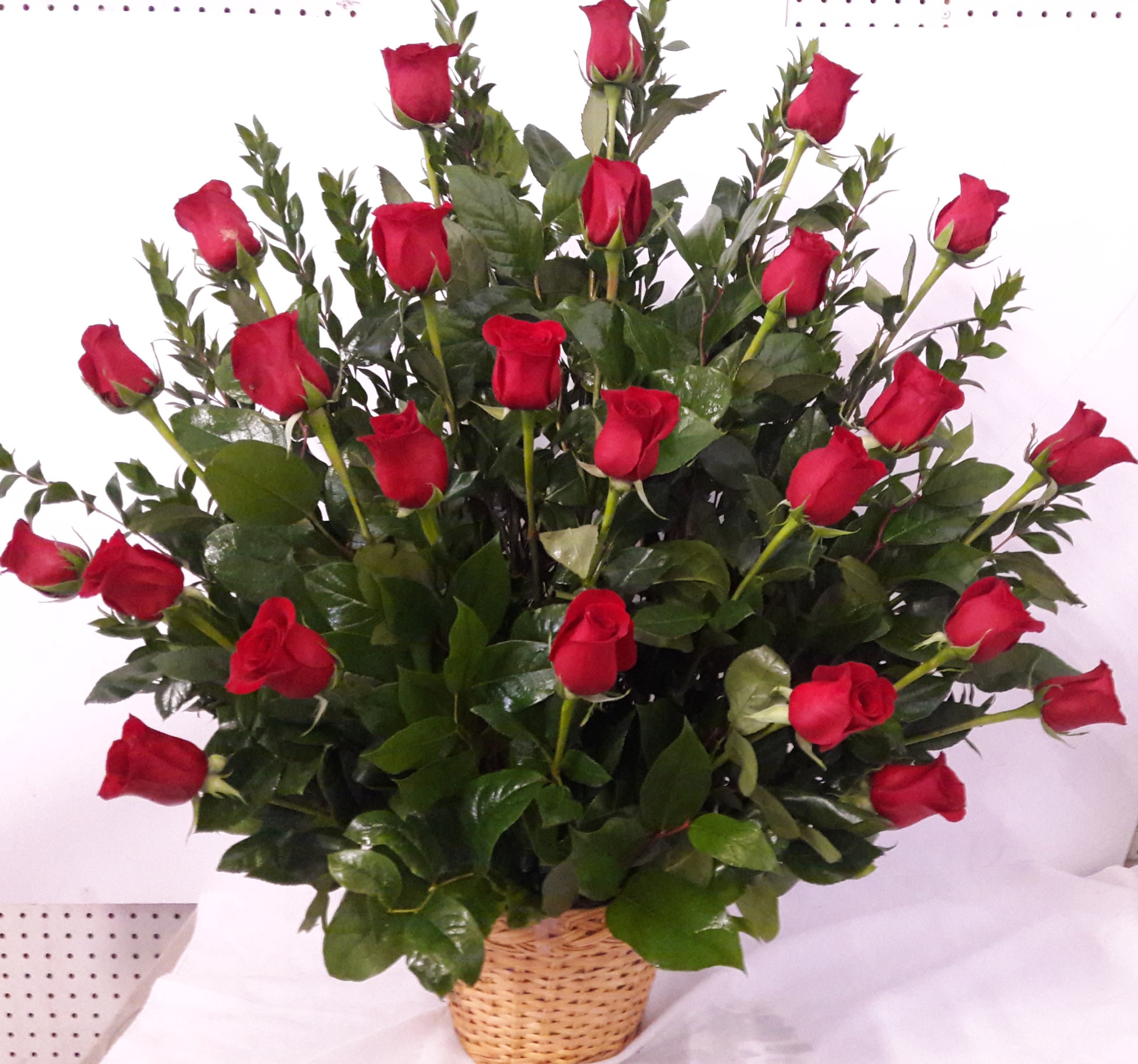 Basket arrangement of red roses with glossy greenery