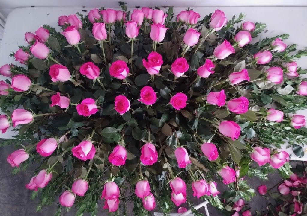 Large arrangement of pink roses laid out in a dense oval shape