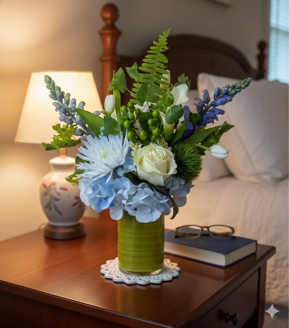 Bouquet of blue and white flowers in a green vase on a bedside table
