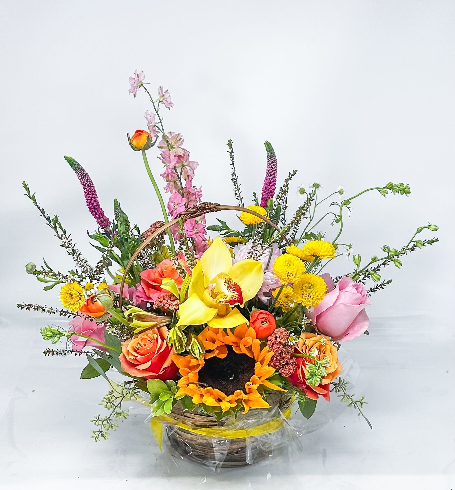 Colorful mixed flower basket with sunflowers, roses, and orchids