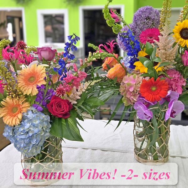 Two colorful mixed flower arrangements in glass vases on a table