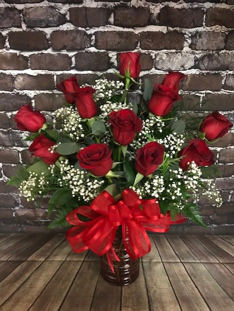 Red roses in a vase with baby's breath and a red ribbon bow