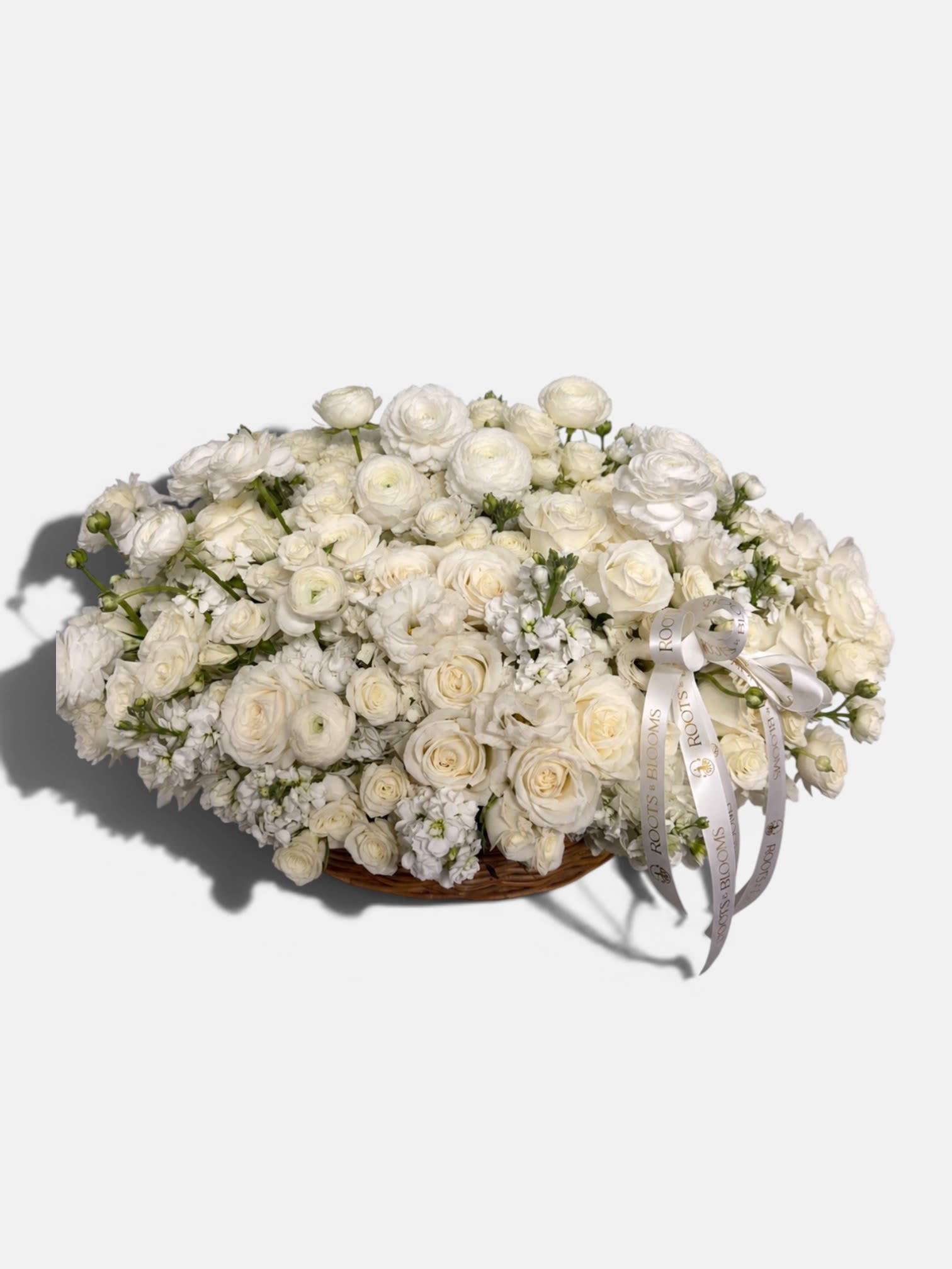 White Whisper Basket  - A luxurious basket, overflowing with premium, white roses, spray roses, ranunculus, and fragrance talk, thought thoughtfully designed in an elegant garden style. It's timeless, all white, palette, symbolize, love, peace, grace, and new beginnings, making it the perfect statement gift for celebrations, sympathy, baby showers,, Or simply to leave a lasting impression.