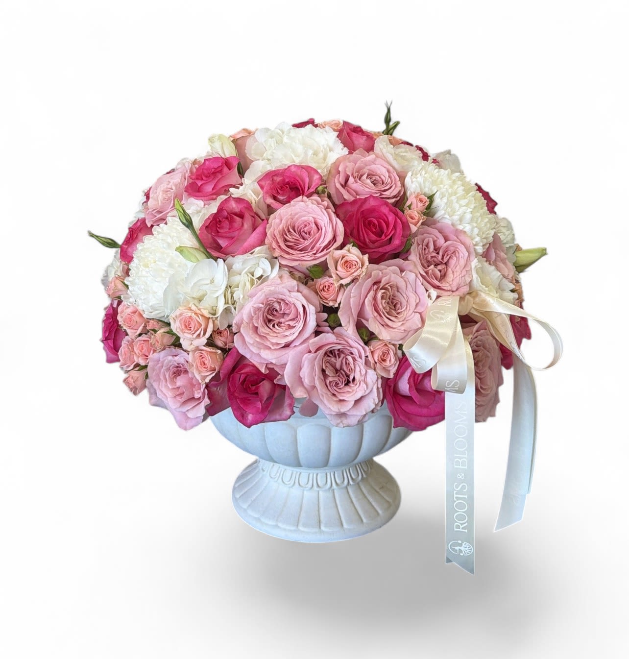 The Signature Grace - A soft, romantic arrangement of blush and pink roses paired with delicate white blooms, elegantly styled in a classic pedestal vase. -timeless, full, and effortlessly graceful.