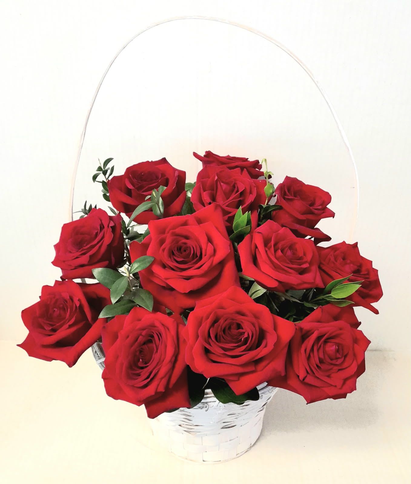 Basket of red roses with greenery