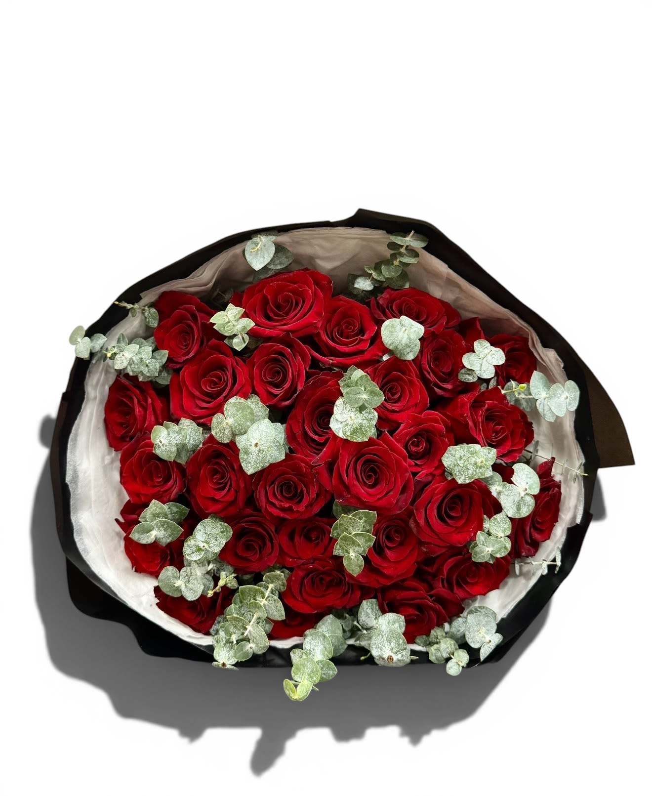 Velvet Rouge Bouquet - A rich, romantic bouquet of premium red roses accented with soft eucalyptus, wrapped in sleek black and ivory tones for a bold, timeless statement.