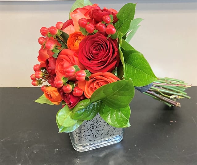 Bouquet of red and orange roses in a square glass vase