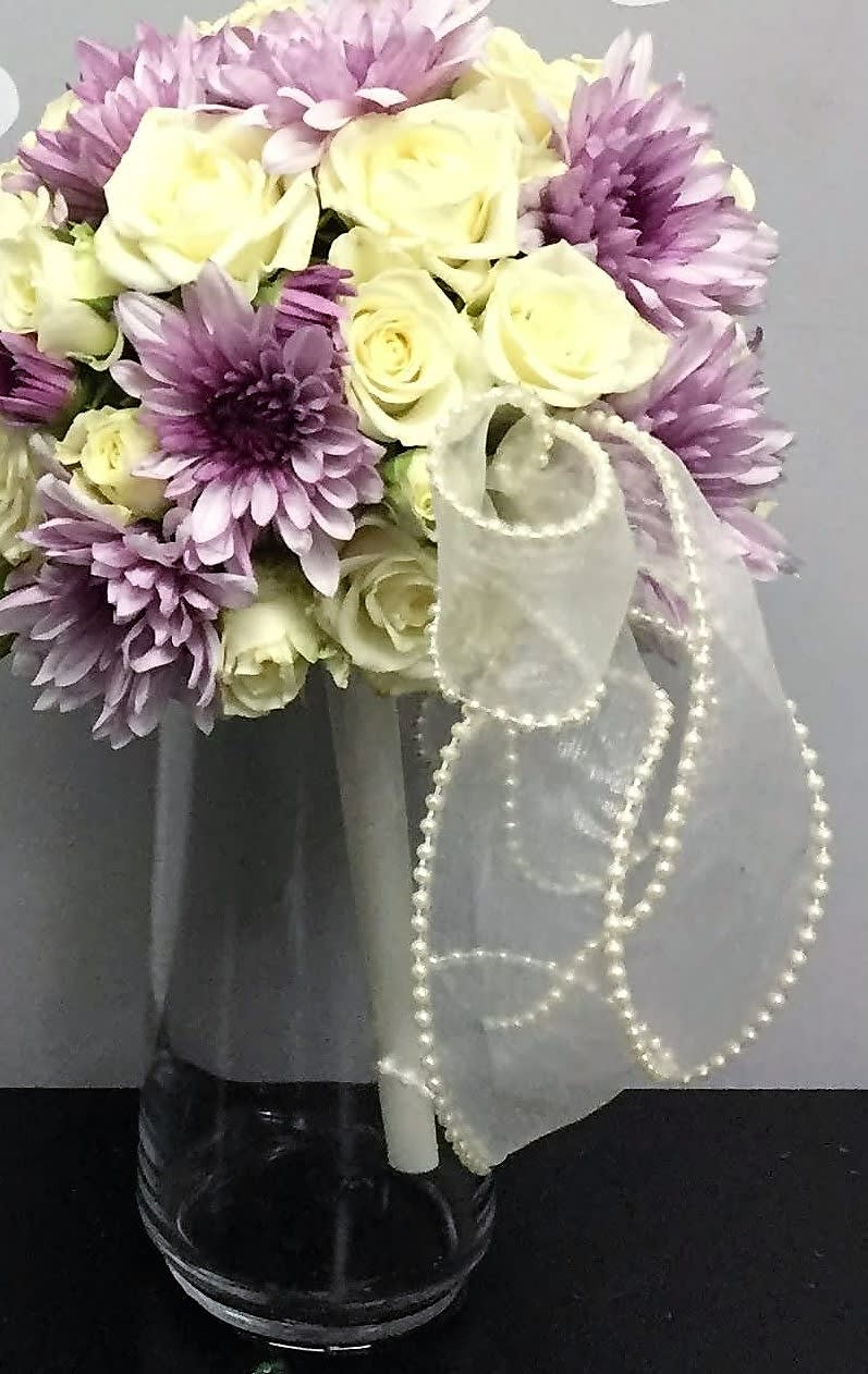 Bouquet of cream roses and lavender chrysanthemums in a glass vase with a sheer ribbon