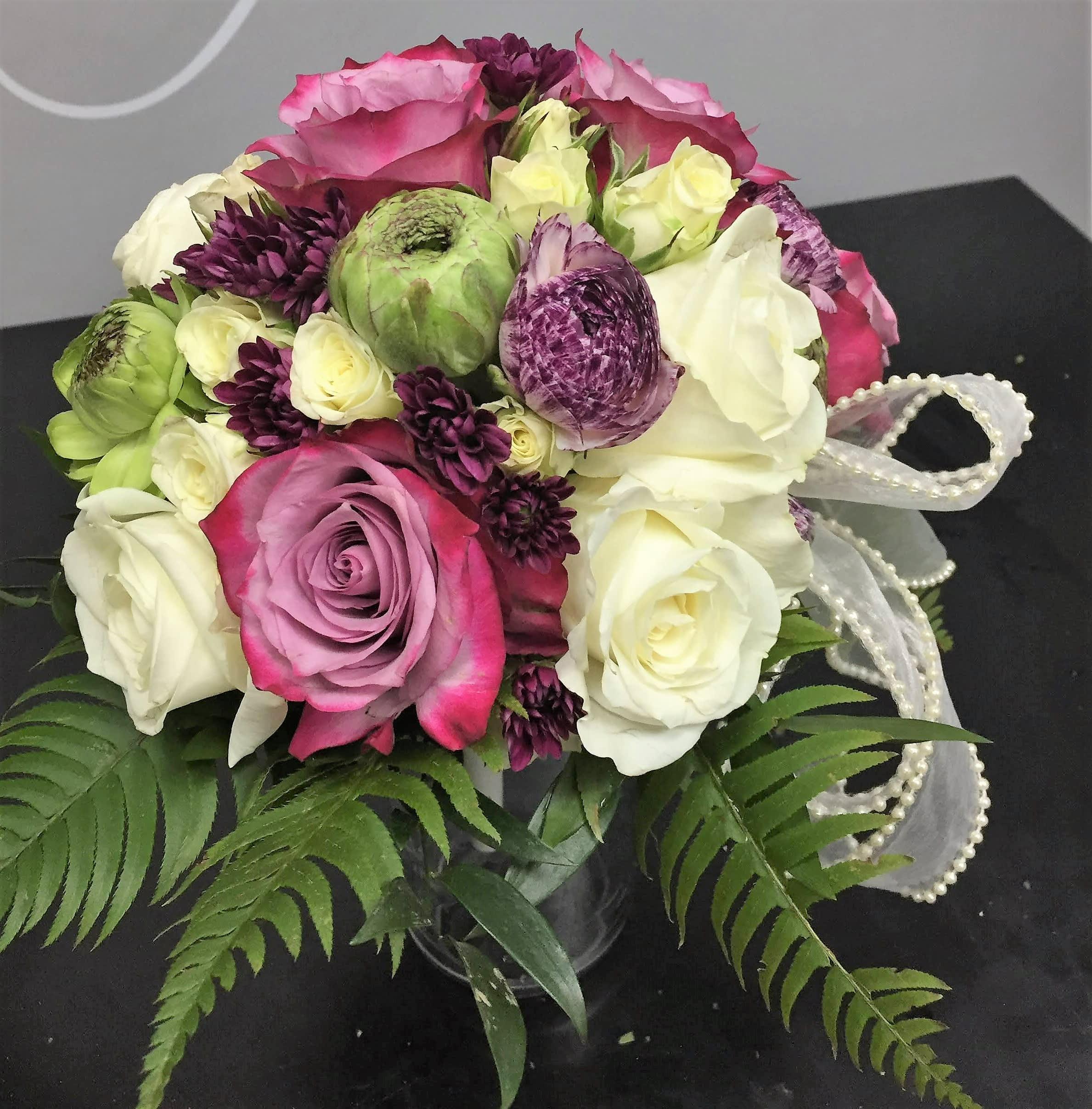 Bouquet of pink, white, and purple roses with ribbon trim