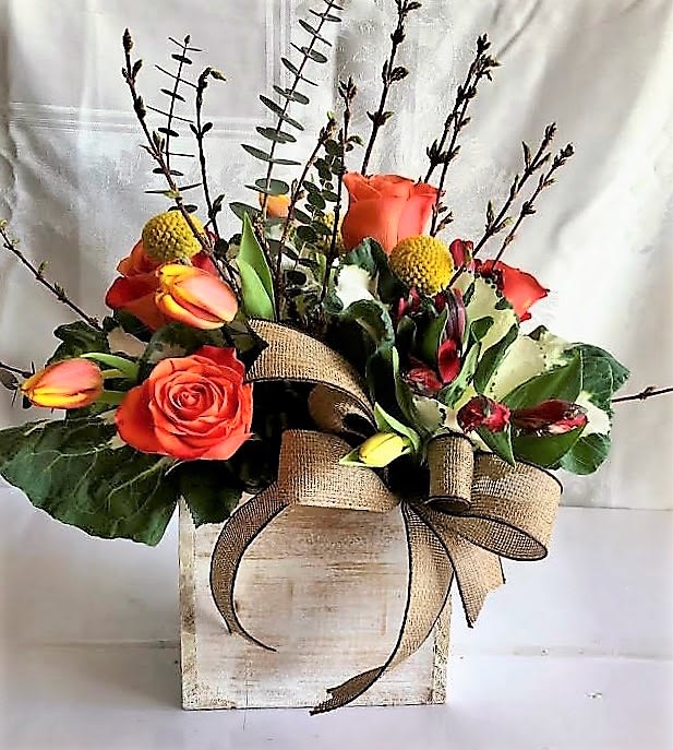 Orange roses in a rustic wooden box with a burlap bow
