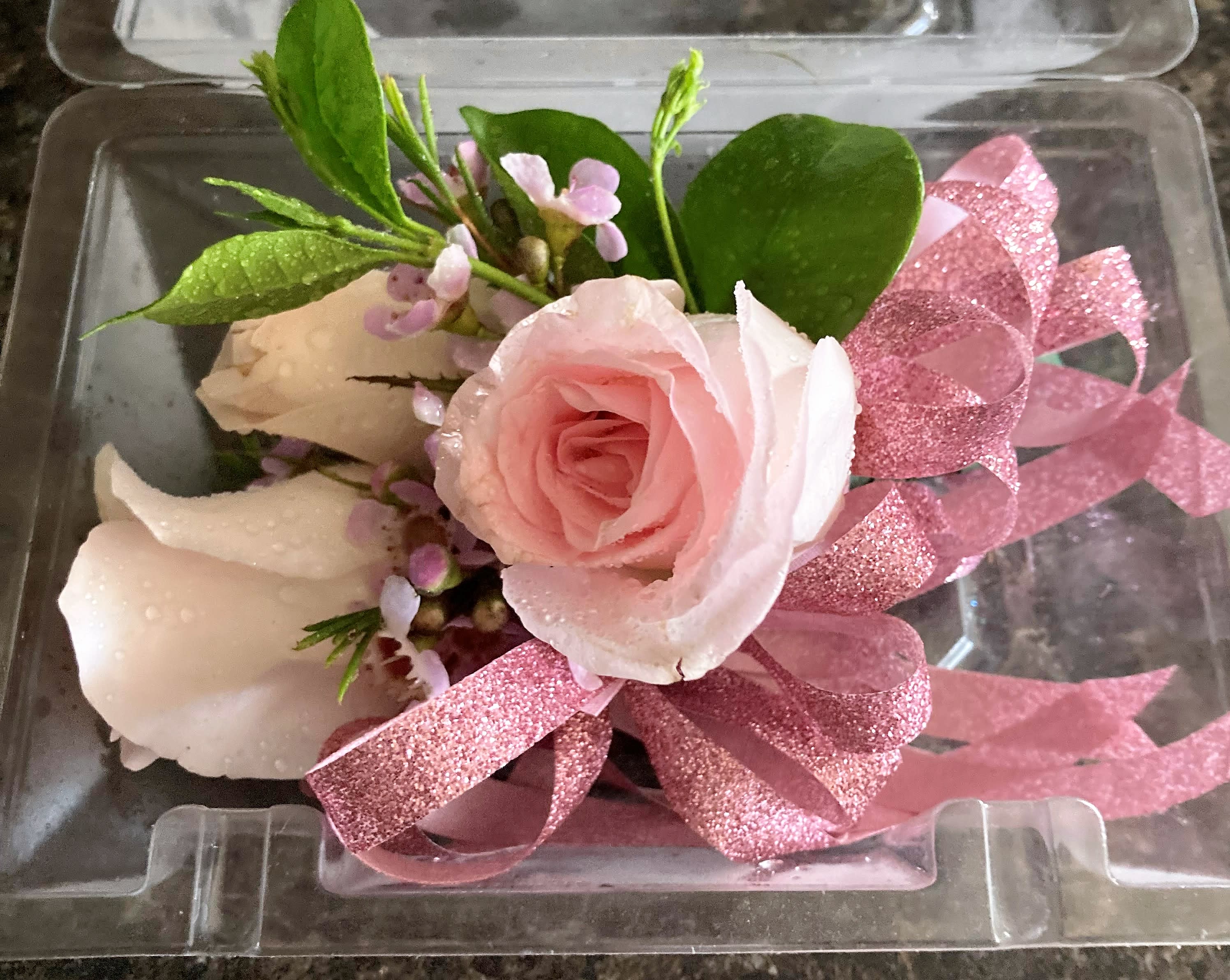 Pink rose boutonniere with glittery ribbon in a clear plastic box