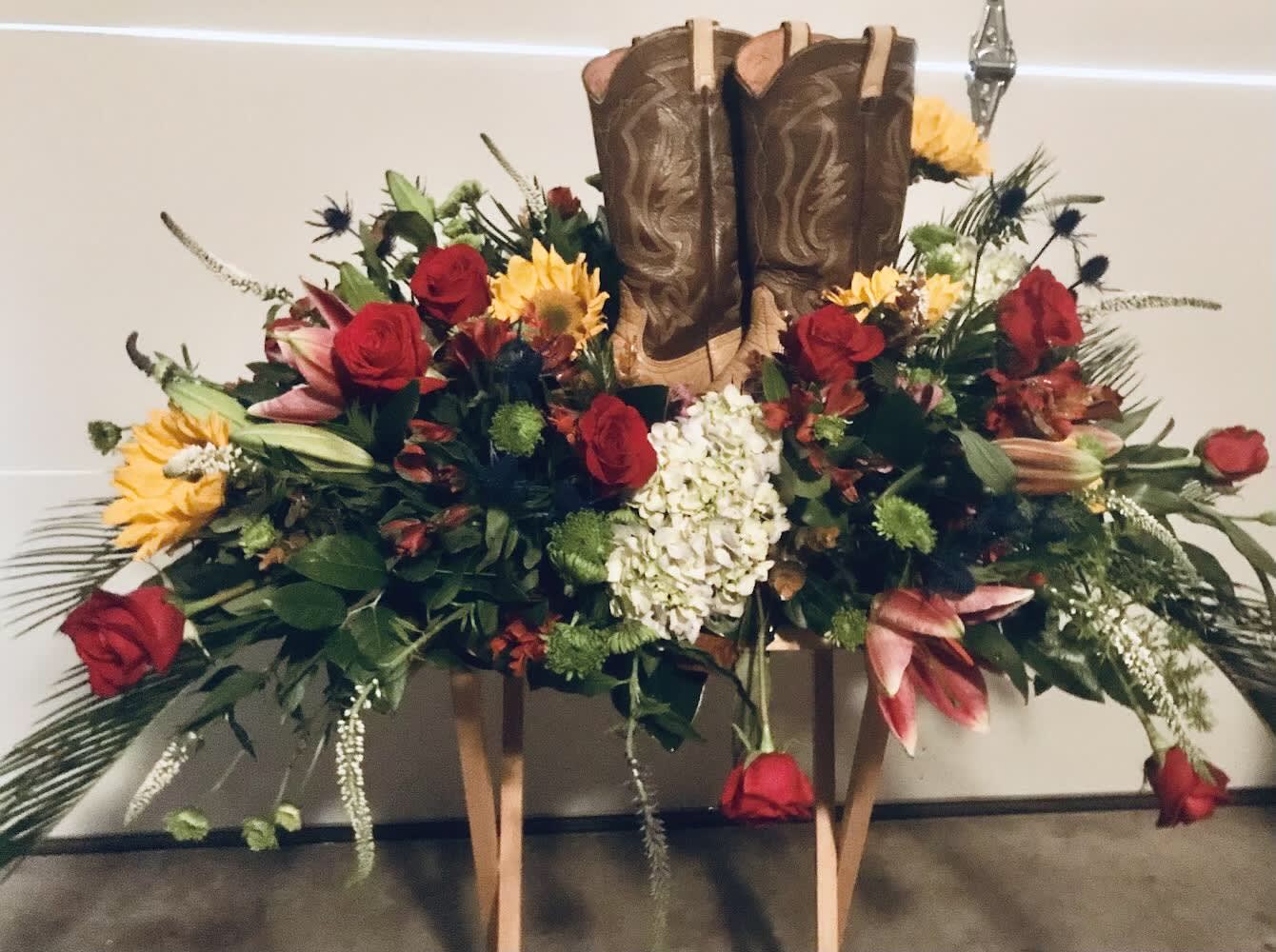 Cowboy boots surrounded by a floral arrangement of roses and lilies