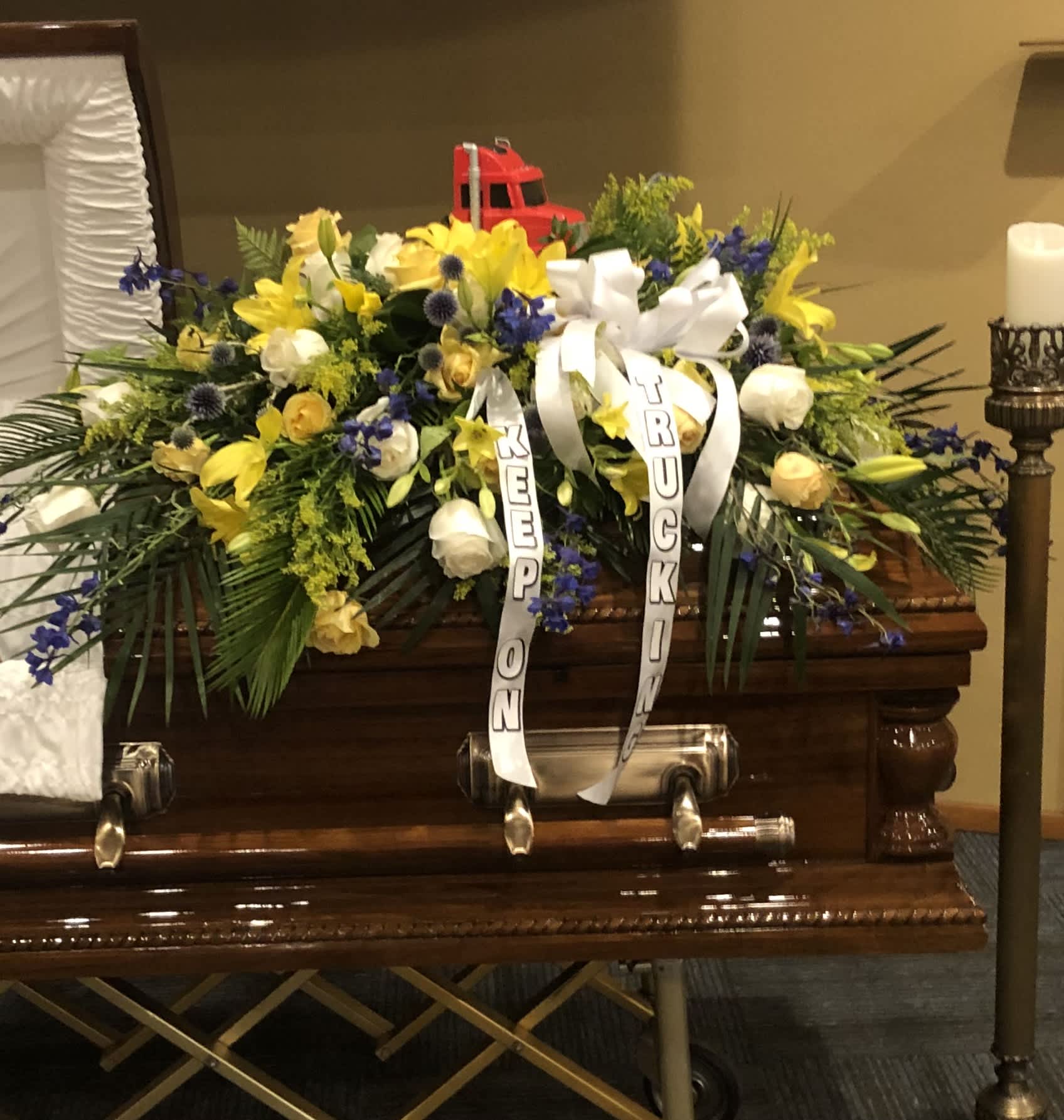 Large funeral casket spray with yellow, white, and blue flowers