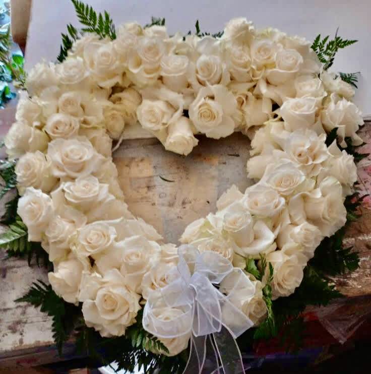 Heart-shaped wreath of white roses with a sheer bow
