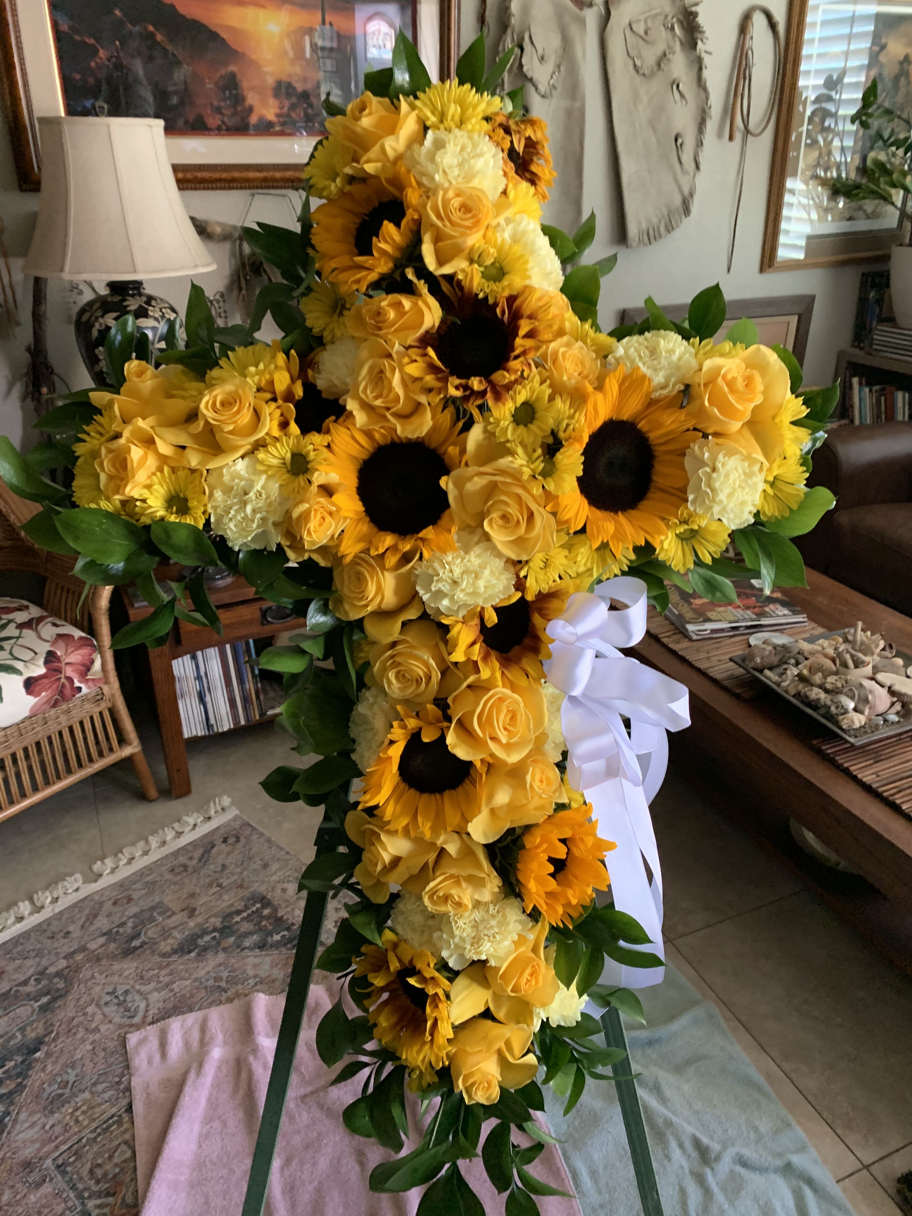 Tall yellow floral standing spray with sunflowers, roses, and a white ribbon